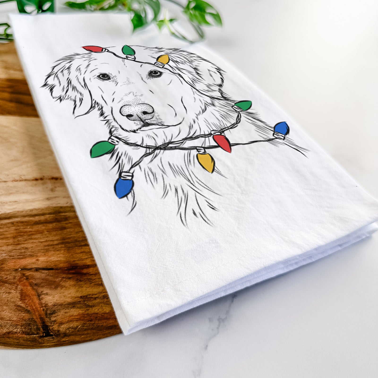Hand-drawn sketch of Spencer the Golden Retriever wrapped in Christmas lights on a tea towel