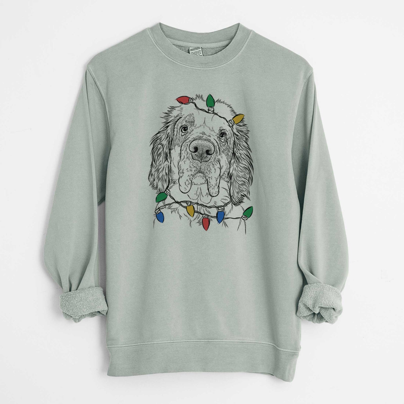 Hand-drawn sketch of Sully the Clumber Spaniel wrapped in Christmas lights on a Sage Unisex pigment dyed crew sweatshirt