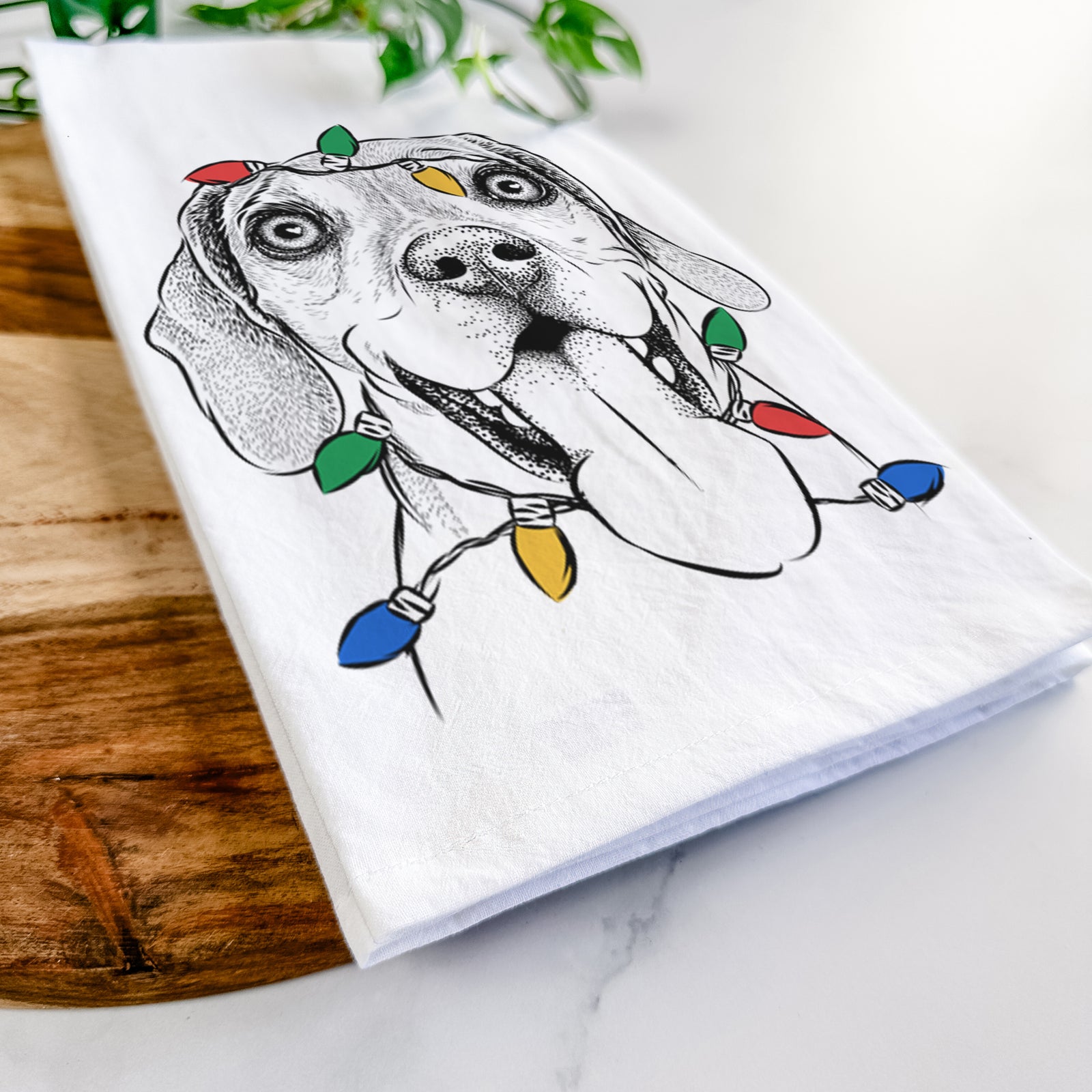 Hand-drawn sketch of Sunny the Beagle wrapped in Christmas lights on a tea towel