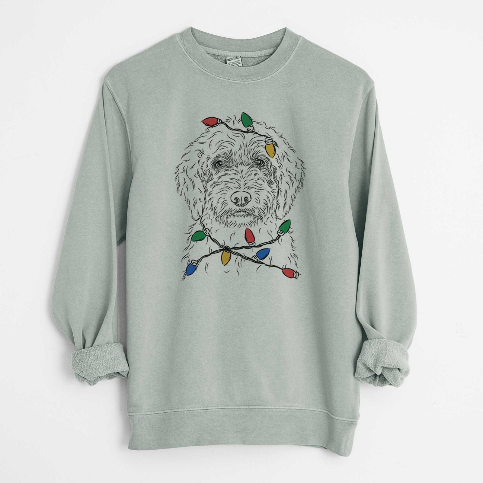 Hand-drawn sketch of Teddy the Labradoodle wrapped in Christmas lights on a Sage Unisex pigment dyed crew sweatshirt