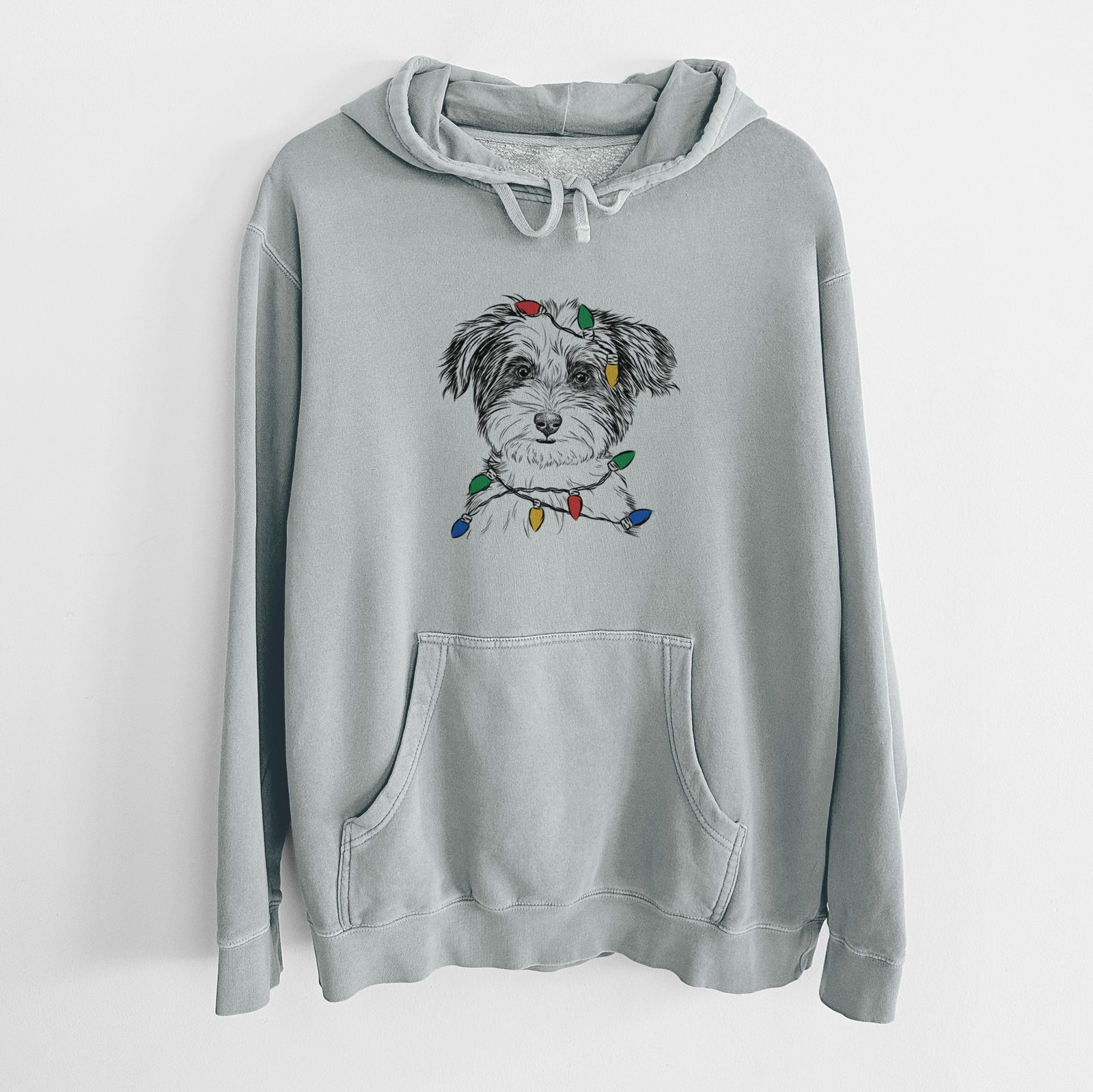 Hand-drawn sketch of Teddy the Havanese wrapped in Christmas lights on a Sage Unisex pigment dyed hoodie