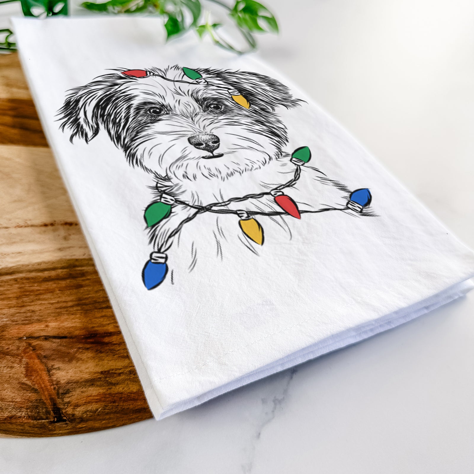 Hand-drawn sketch of Teddy the Havanese wrapped in Christmas lights on a tea towel