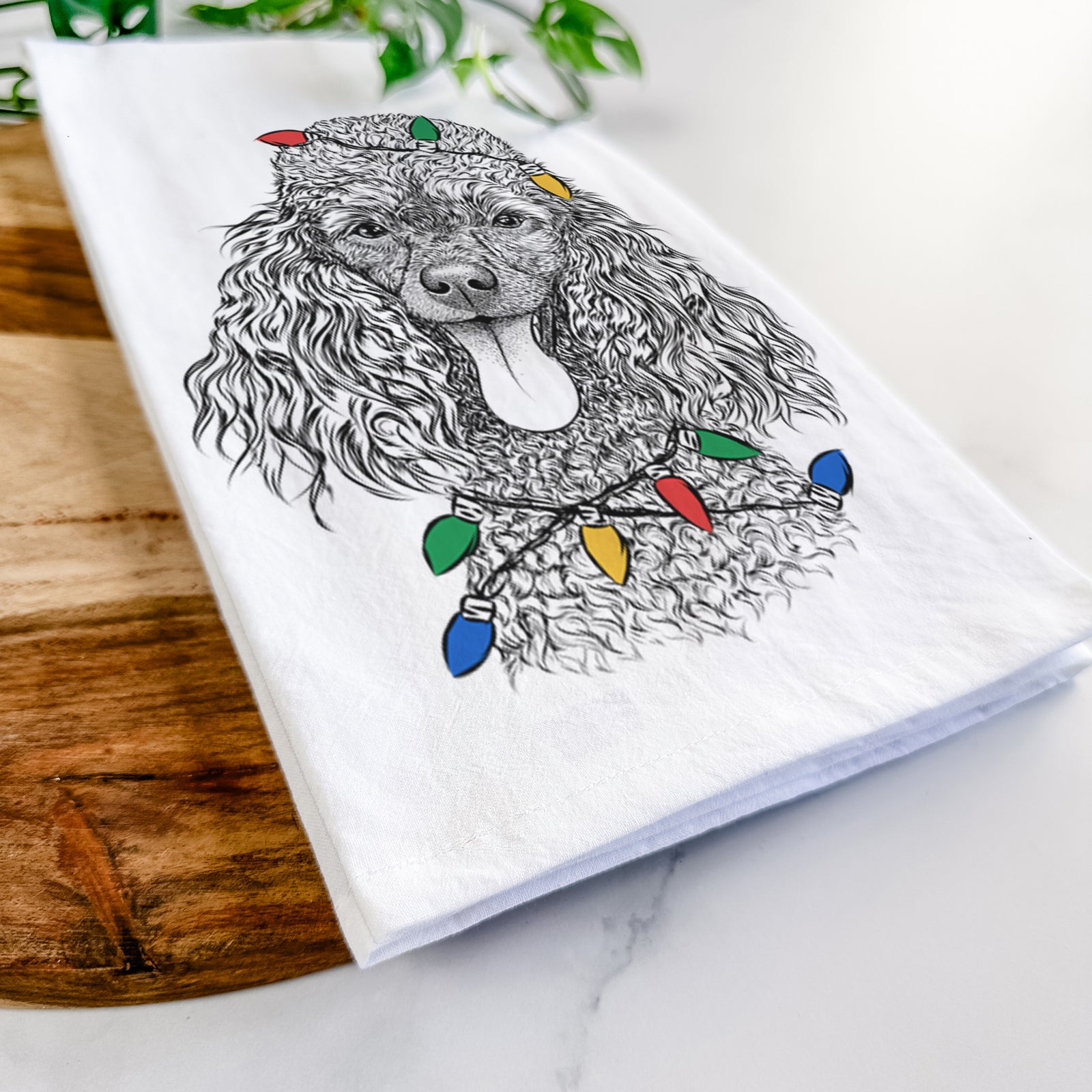 Hand-drawn sketch of Teddy the Mini Poodle wrapped in Christmas lights on a tea towel