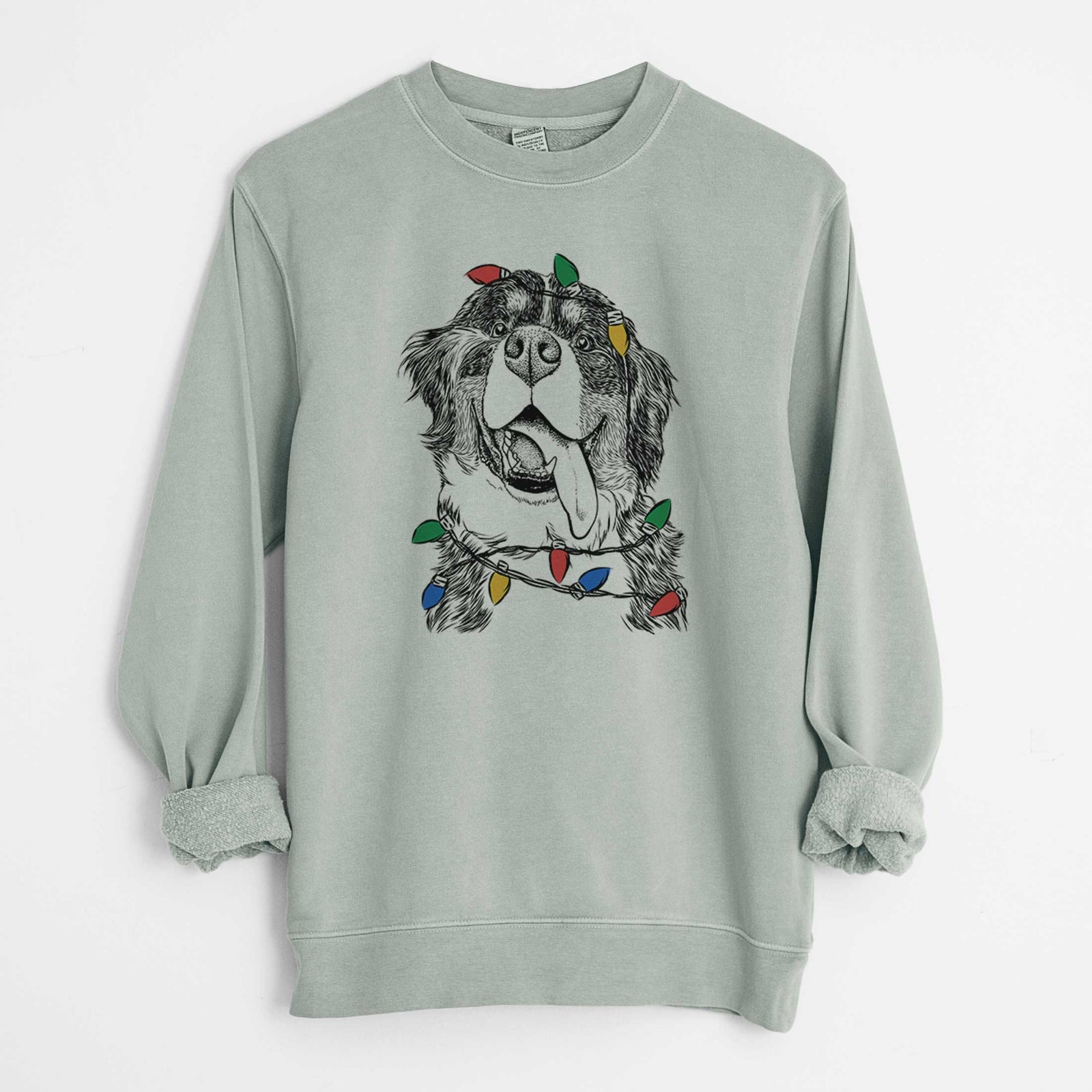 Hand-drawn sketch of Theo the Bernese Mountain Dog wrapped in Christmas lights on a Sage Unisex pigment dyed crew sweatshirt
