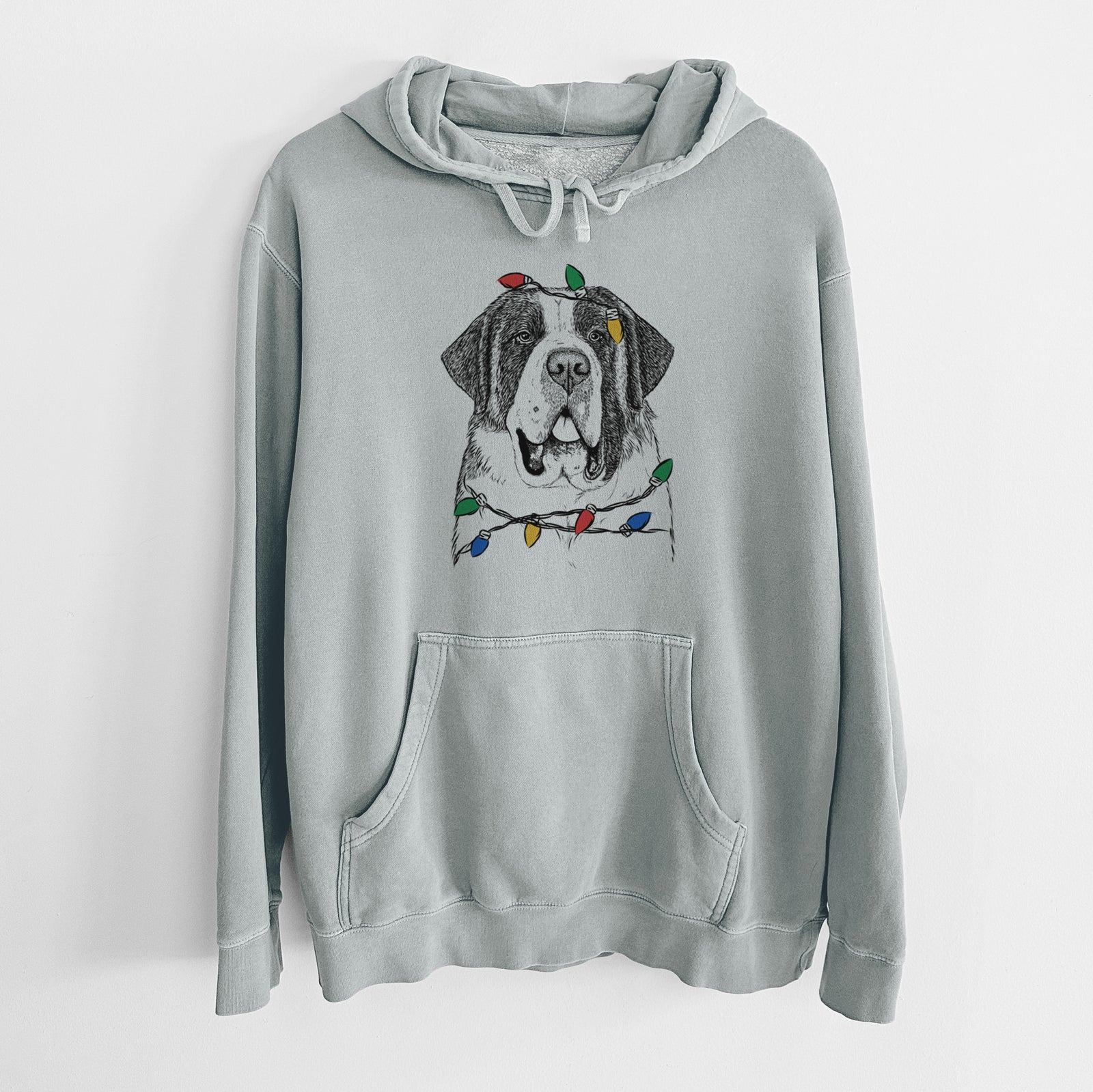 Hand-drawn sketch of Thor the Saint Bernard wrapped in Christmas lights on a Sage Unisex pigment dyed hoodie