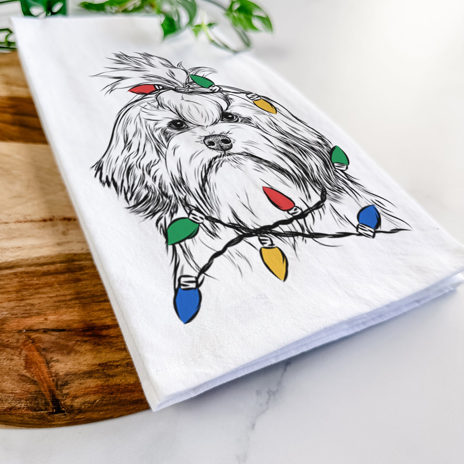 Hand-drawn sketch of Tootsie the Lowchen wrapped in Christmas lights on a tea towel