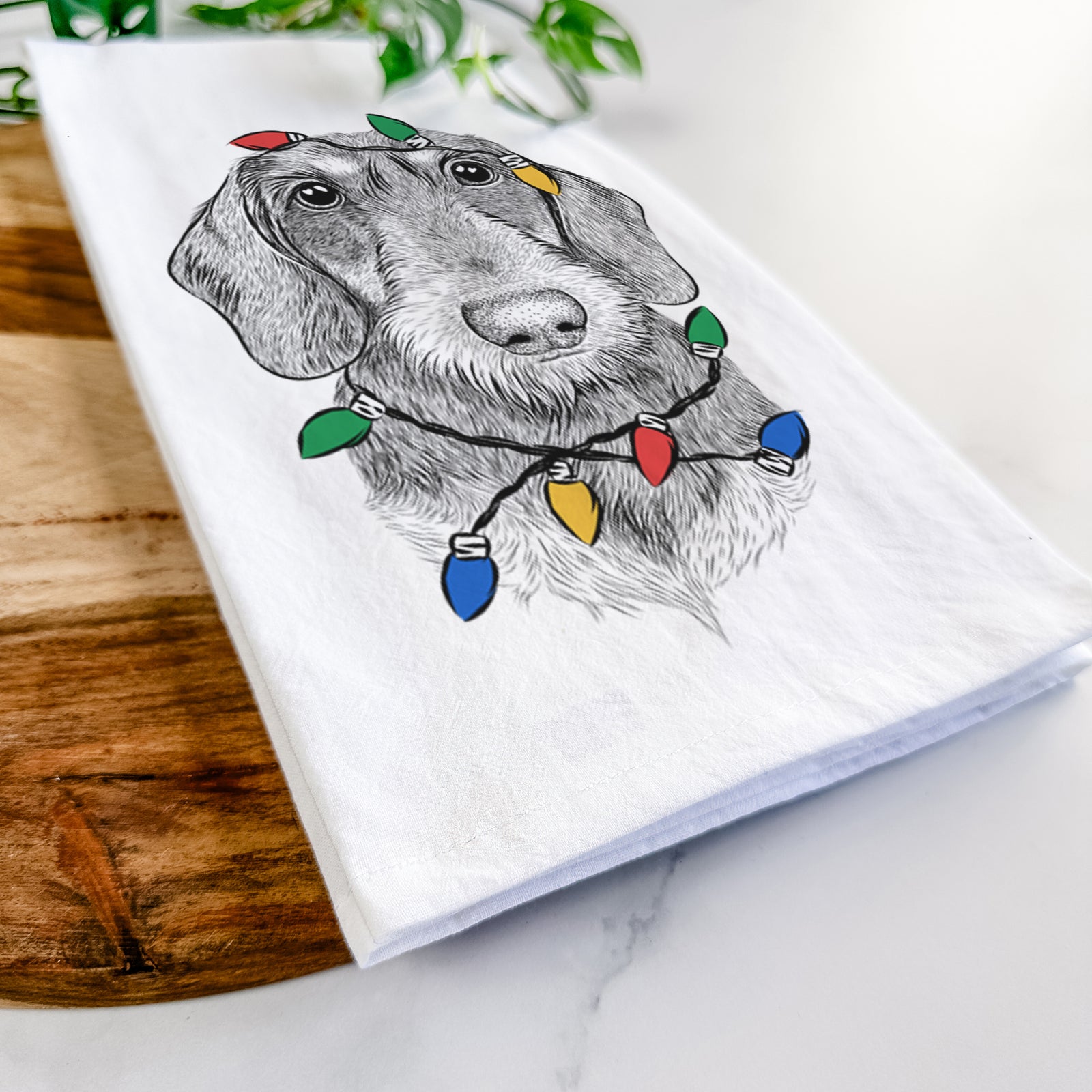 Hand-drawn sketch of Truman the Wirehaired Dachshund wrapped in Christmas lights on a tea towel