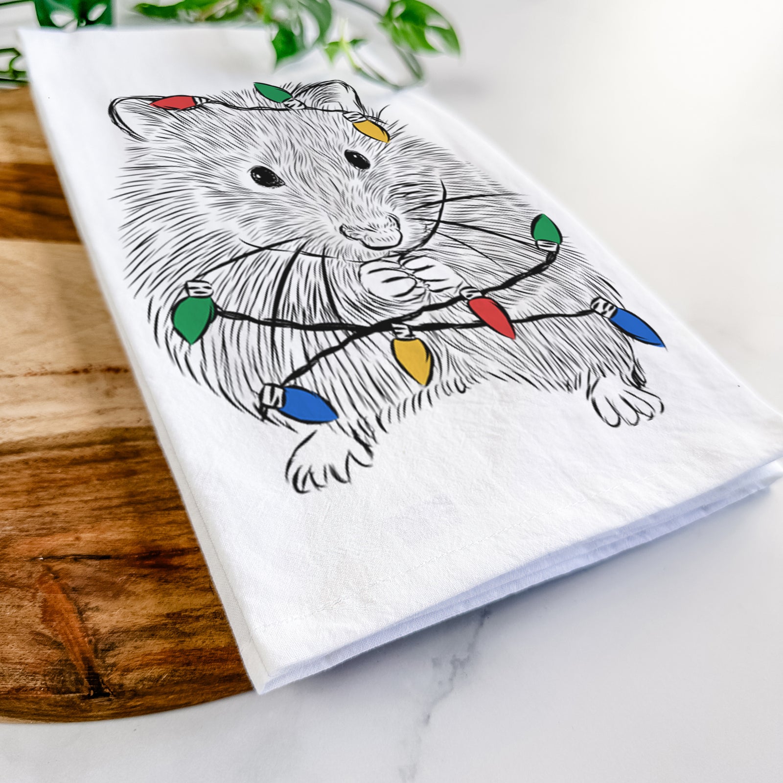 Hand-drawn sketch of Twitch the Hamster wrapped in Christmas lights on a tea towel
