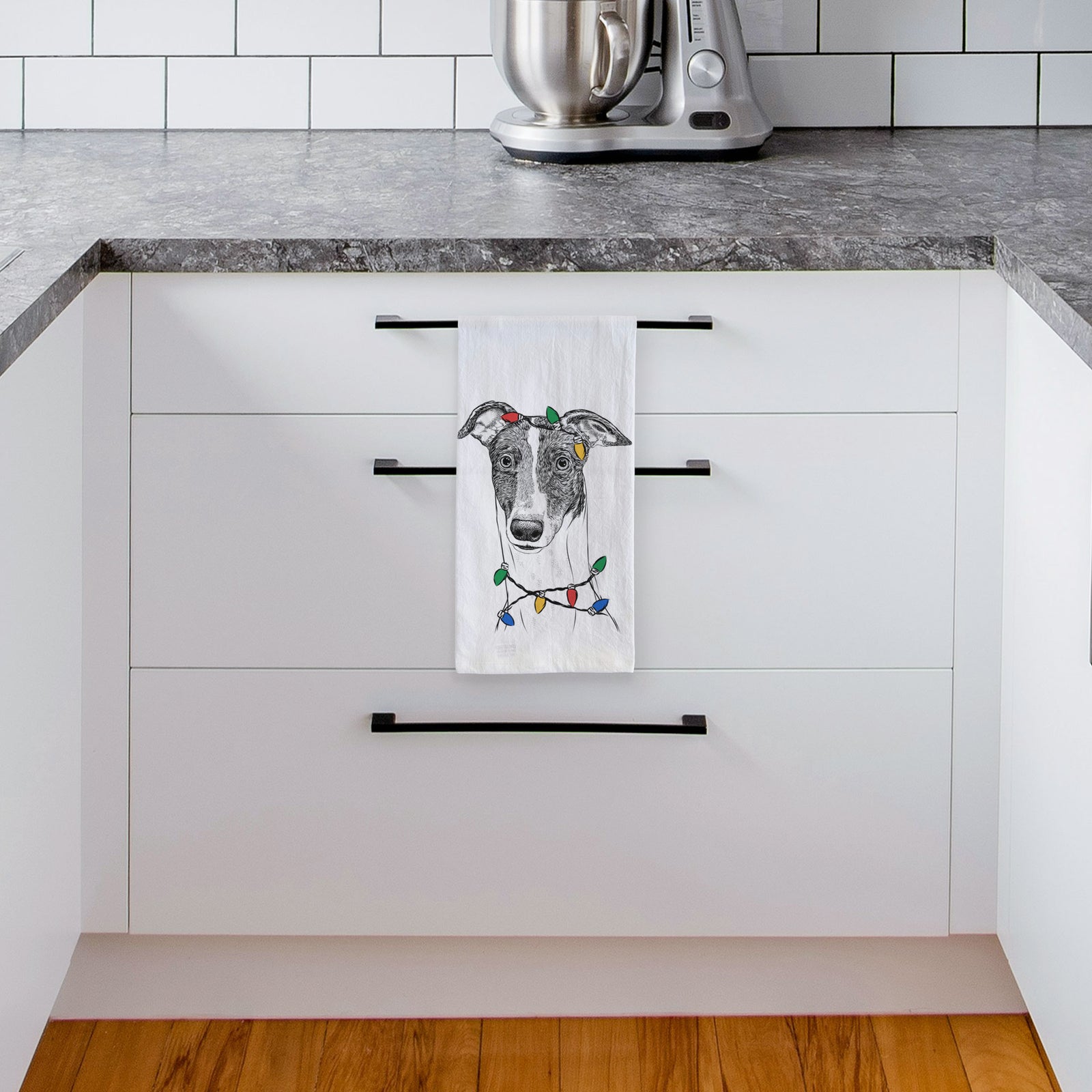 Hand-drawn sketch of Vyncent the Greyhound wrapped in Christmas lights on a tea towel, hanging on an oven door in a kitchen
