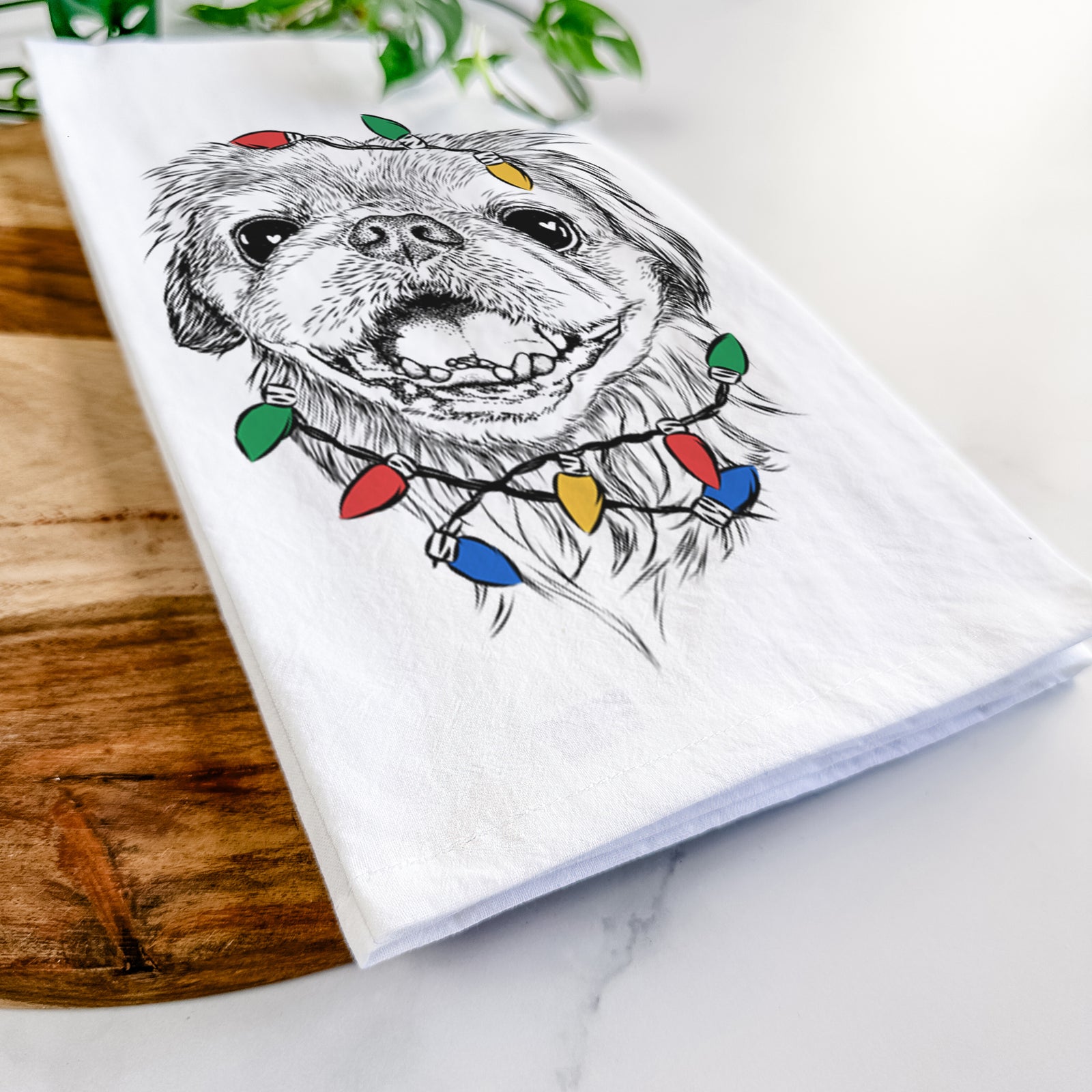 Hand-drawn sketch of Wally the Pekingese wrapped in Christmas lights on a tea towel