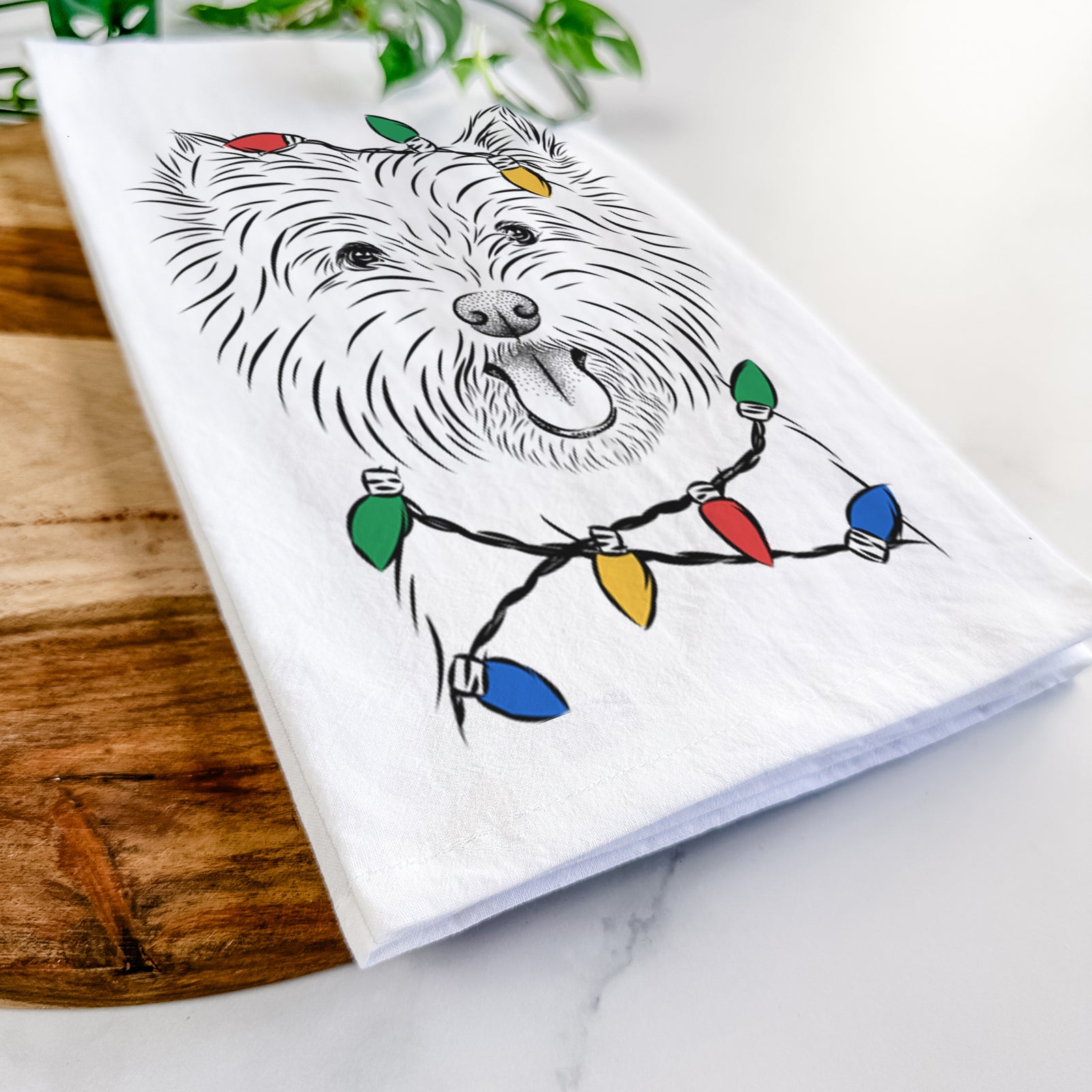 Hand-drawn sketch of Welma the West Highland Terrier wrapped in Christmas lights on a tea towel