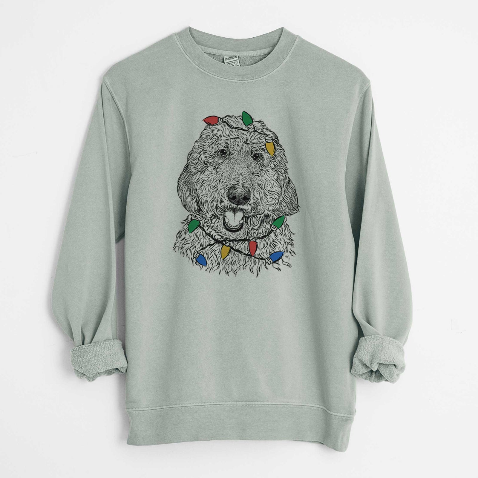 Hand-drawn sketch of Whisper the Goldendoodle wrapped in Christmas lights on a Sage Unisex pigment dyed crew sweatshirt