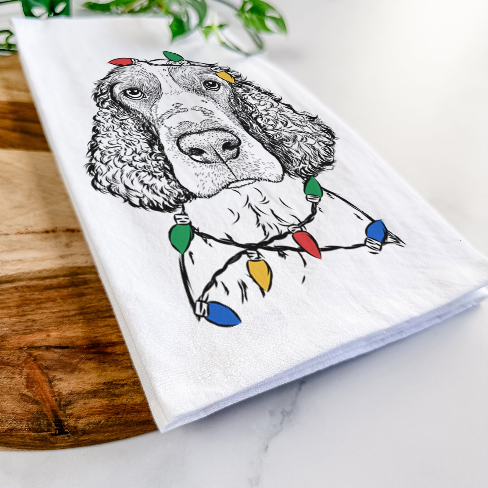 Hand-drawn sketch of Wilbur the English Springer Spaniel wrapped in Christmas lights on a tea towel