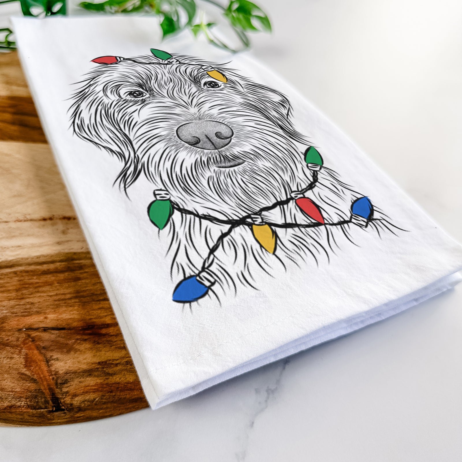 Hand-drawn sketch of Wilkins the Wirehaired Pointing Griffon wrapped in Christmas lights on a tea towel