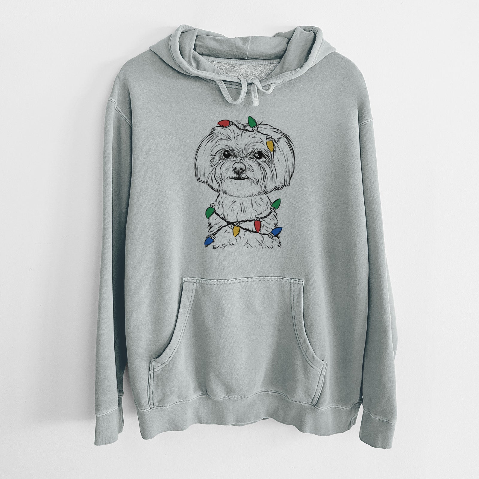 Hand-drawn sketch of Willow the Maltese wrapped in Christmas lights on a Sage Unisex pigment dyed hoodie