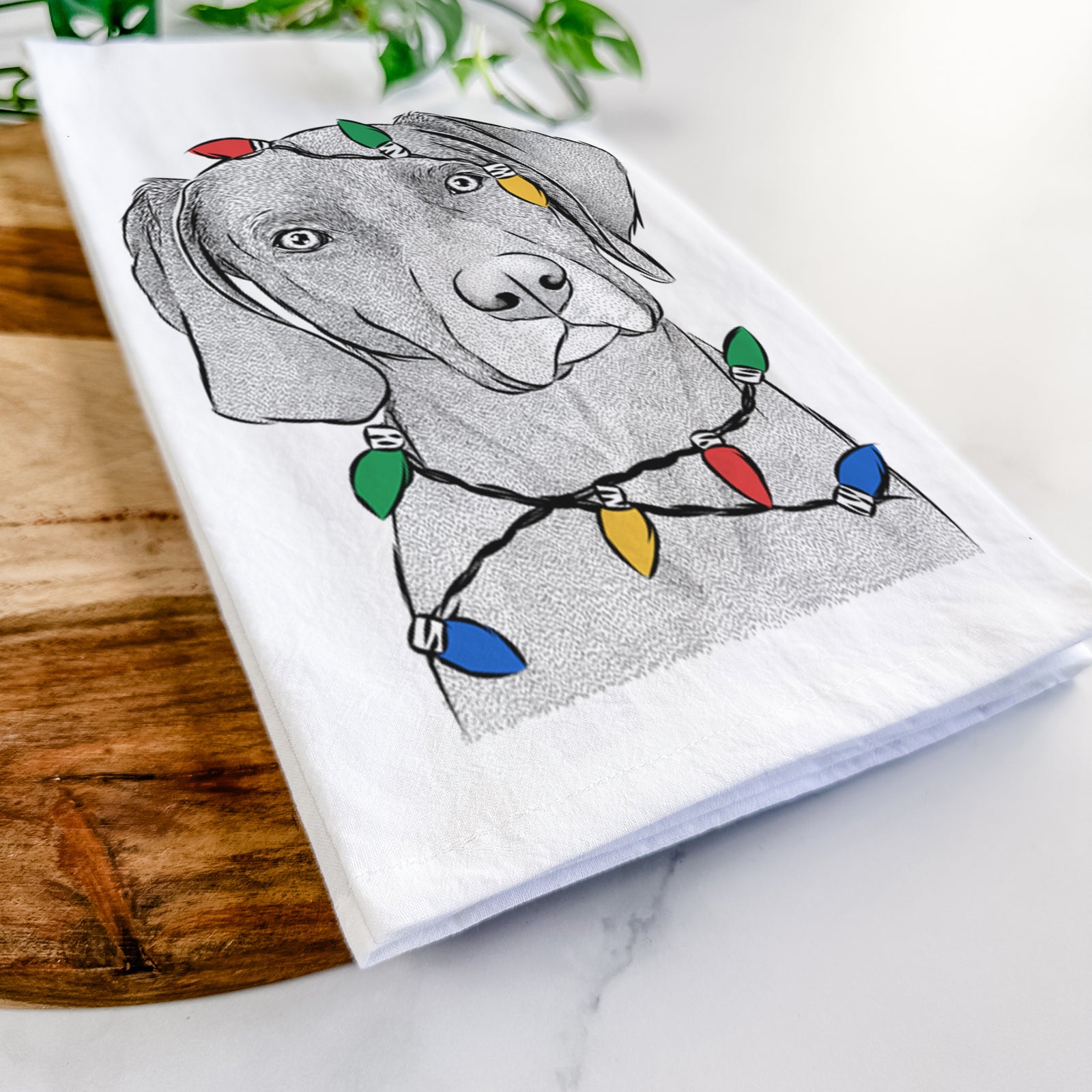 Hand-drawn sketch of Willow the Weizsla wrapped in Christmas lights on a tea towel