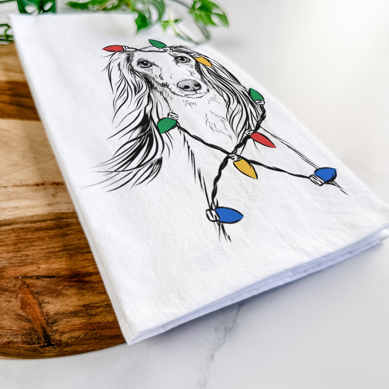 Hand-drawn sketch of Zahra the Saluki wrapped in Christmas lights on a tea towel