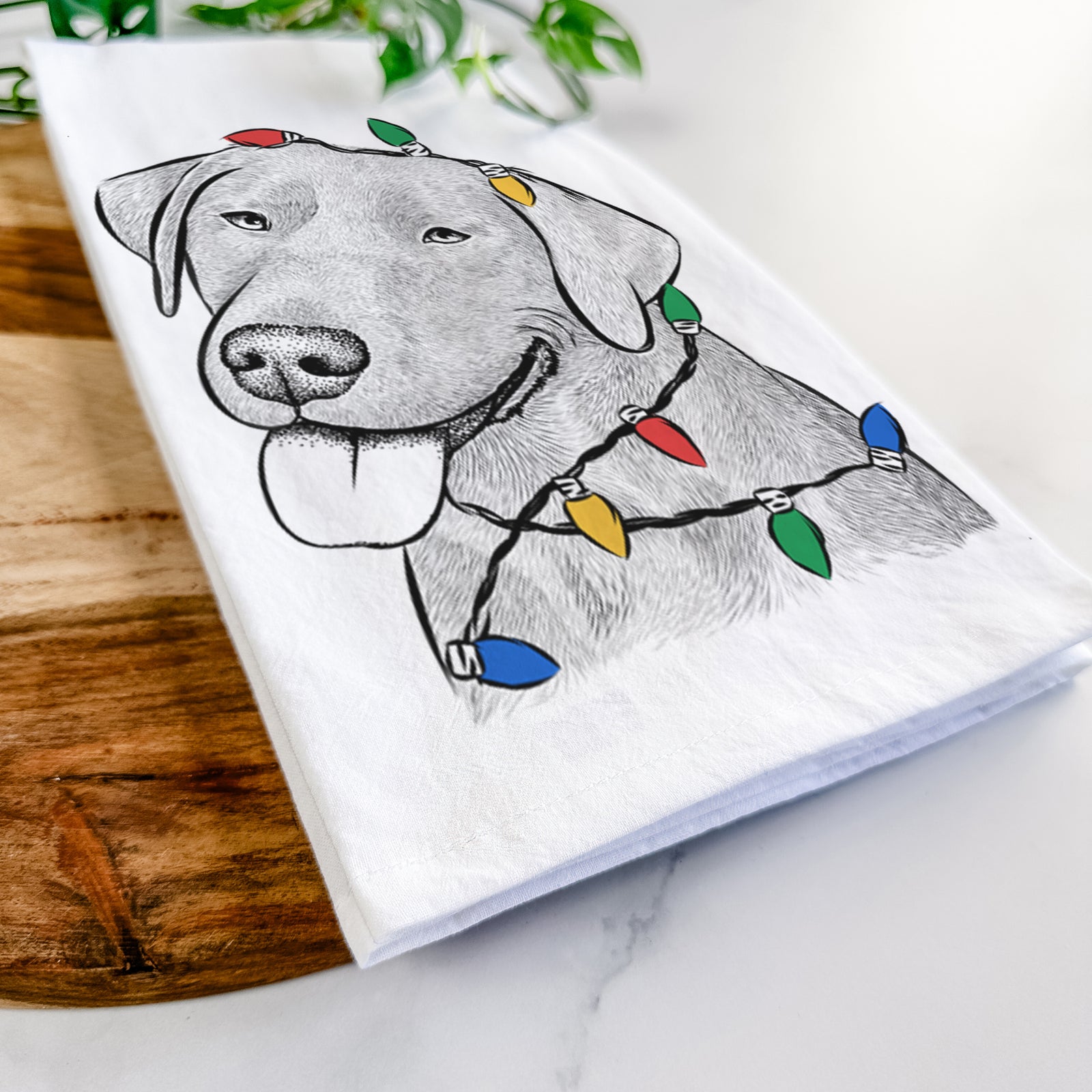 Hand-drawn sketch of Zeppelin the Black Labrador wrapped in Christmas lights on a tea towel