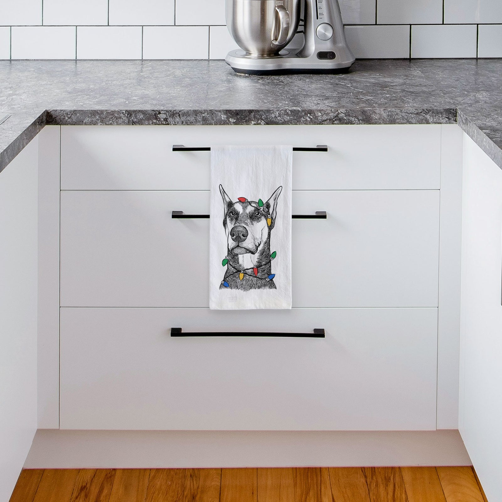 Hand-drawn sketch of Zeus the Doberman Pinscher wrapped in Christmas lights on a tea towel, hanging on an oven door in a kitchen