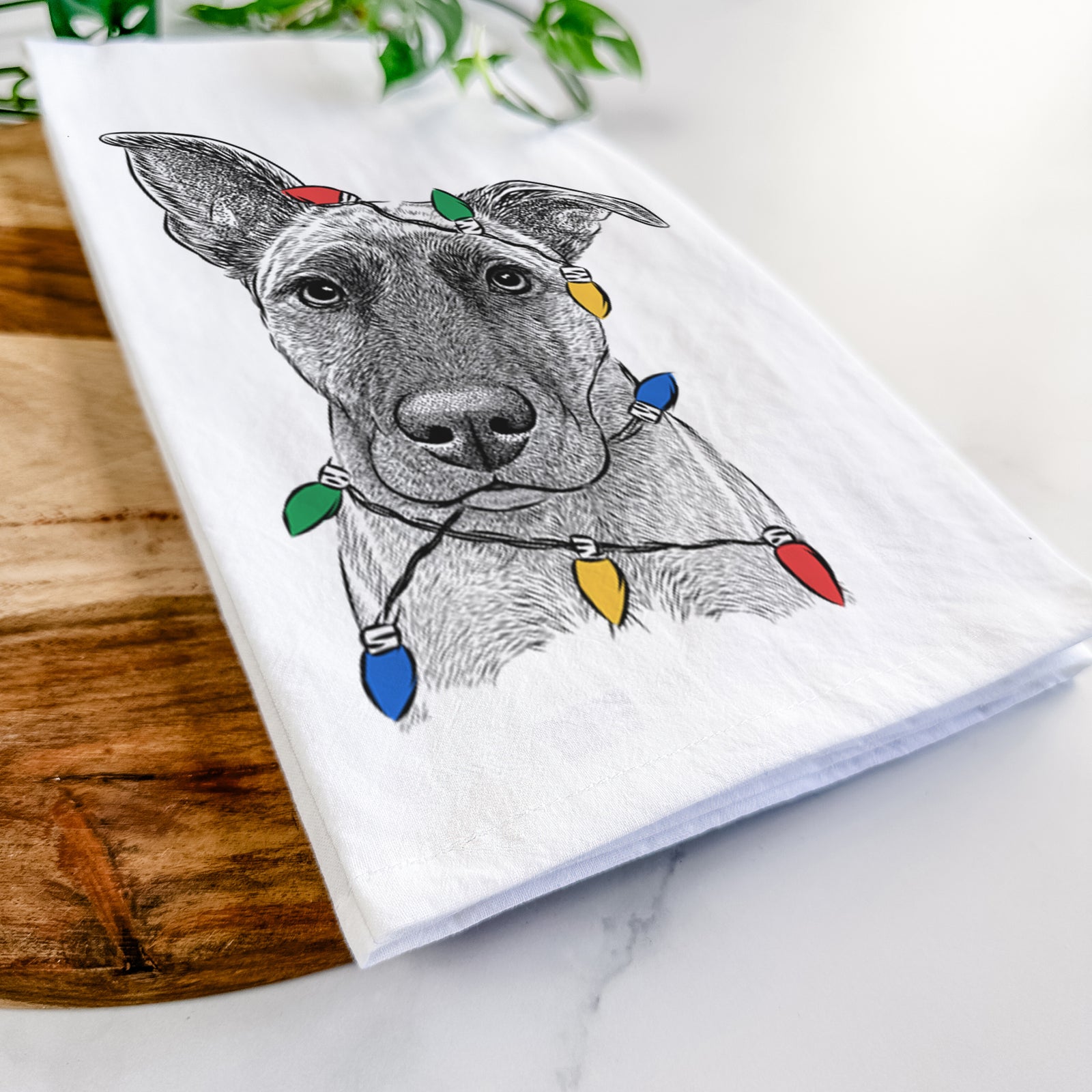 Hand-drawn sketch of Zoey the Mixed Breed wrapped in Christmas lights on a tea towel