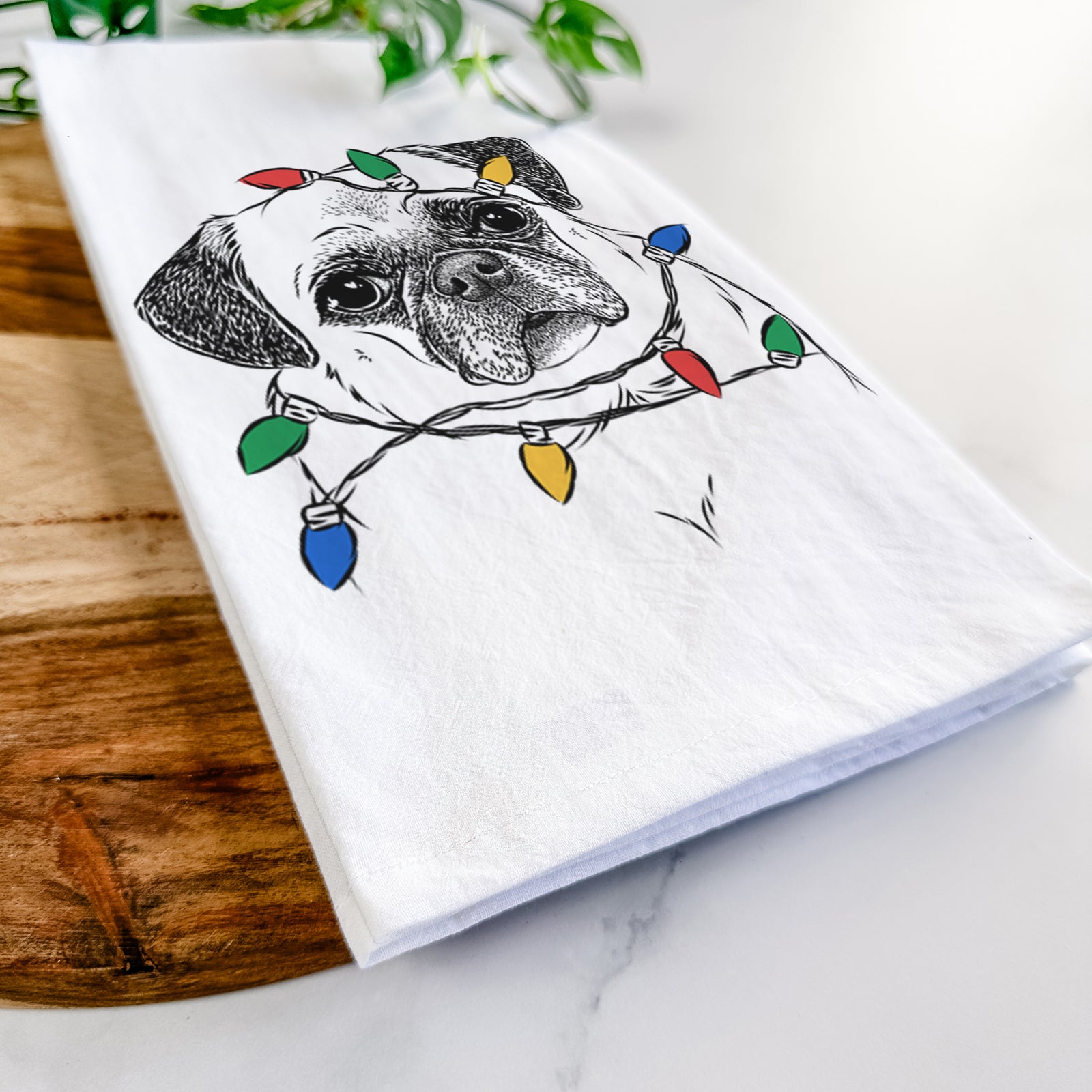 Hand-drawn sketch of Zoey the Pug wrapped in Christmas lights on a tea towel