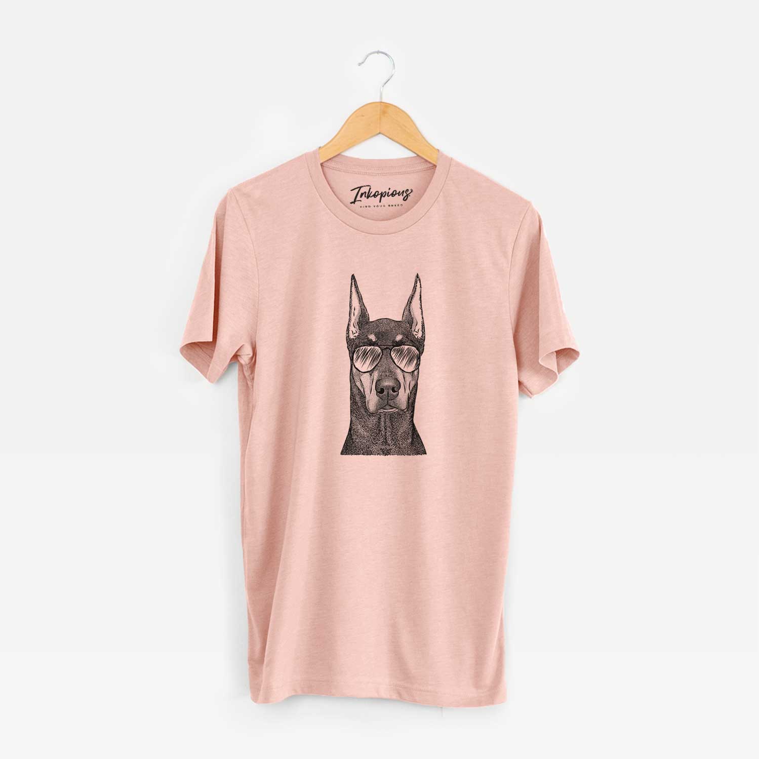 Hand-drawn sketch of Drake the Doberman Pinscher wearing aviator sunglasses on a Peach Unisex crewneck