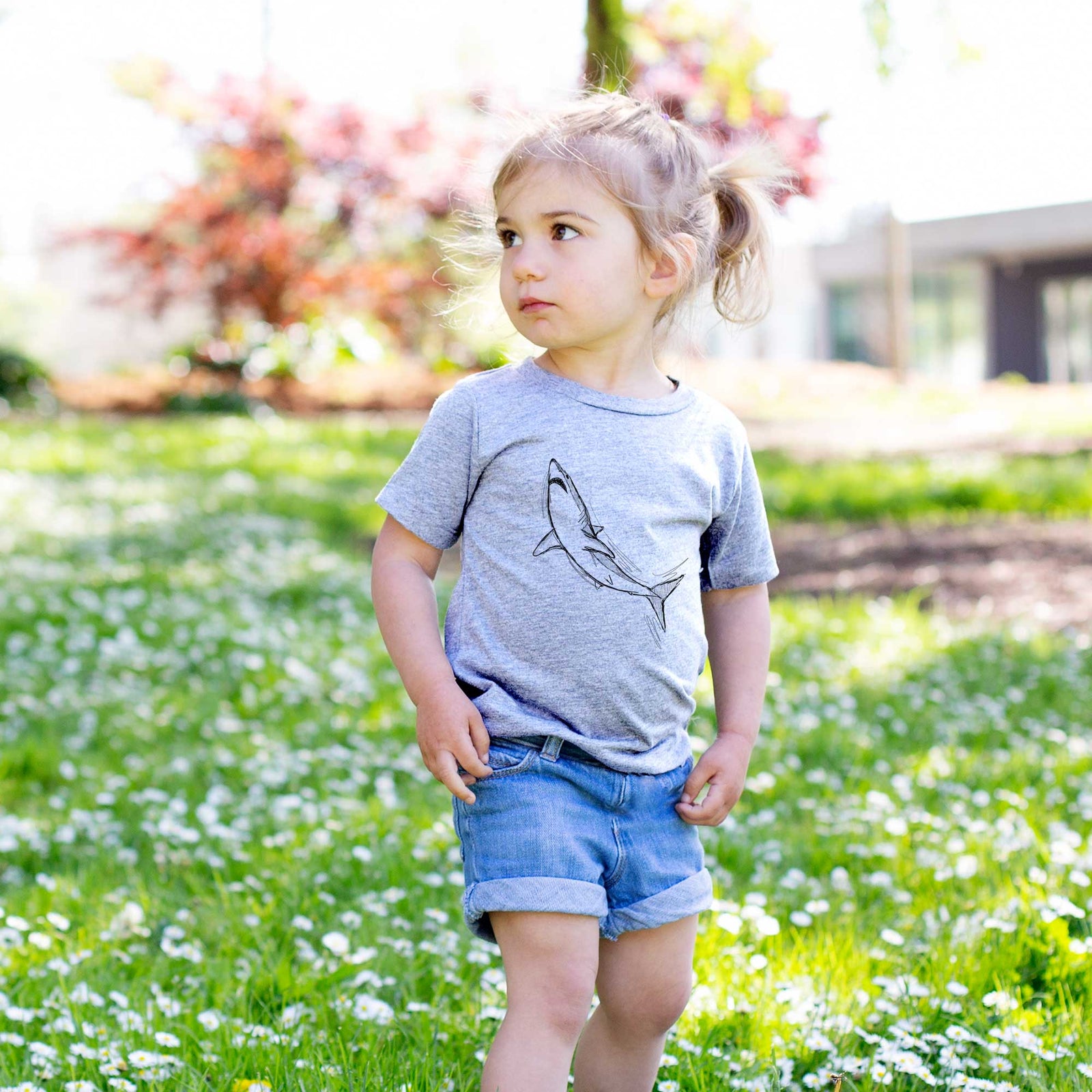 Hand-drawn sketch of Anchor the Mako Shark on a kids' shirt, worn by a girl