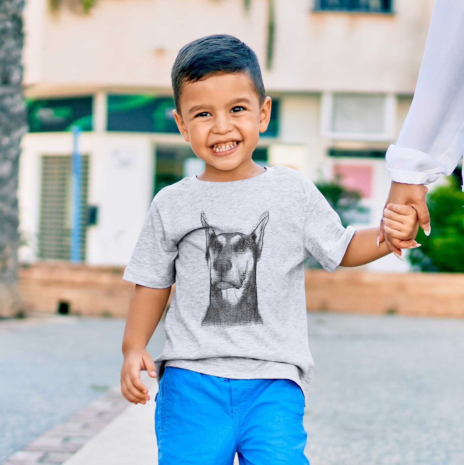 Hand-drawn sketch of Zeus the Doberman Pinscher on a kids' shirt, worn by a boy
