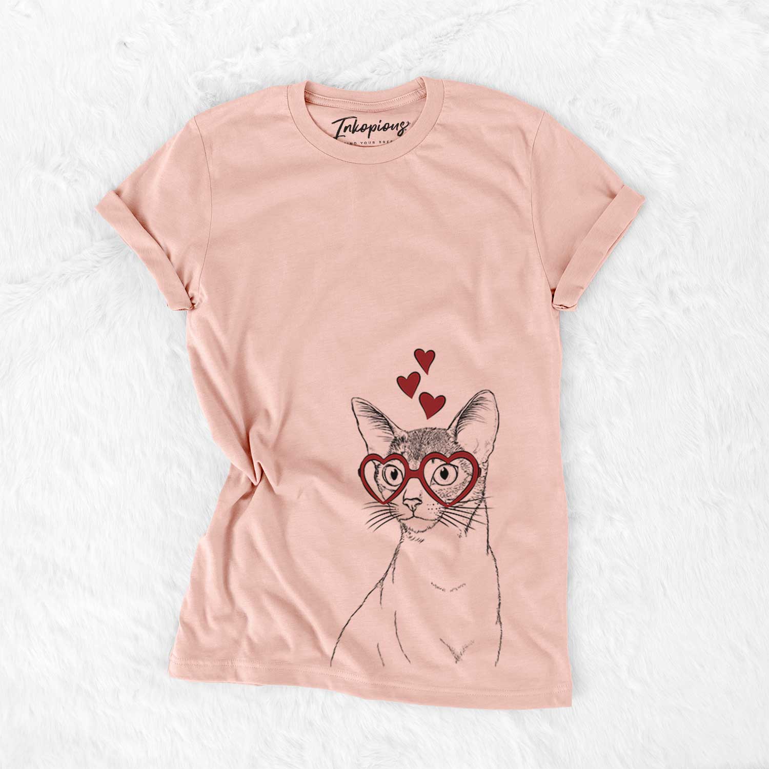 Hand-drawn sketch of Cedric the Abyssinian Cat wearing heart-shaped glasses on a Peach Bella Canvas Unisex Crewneck