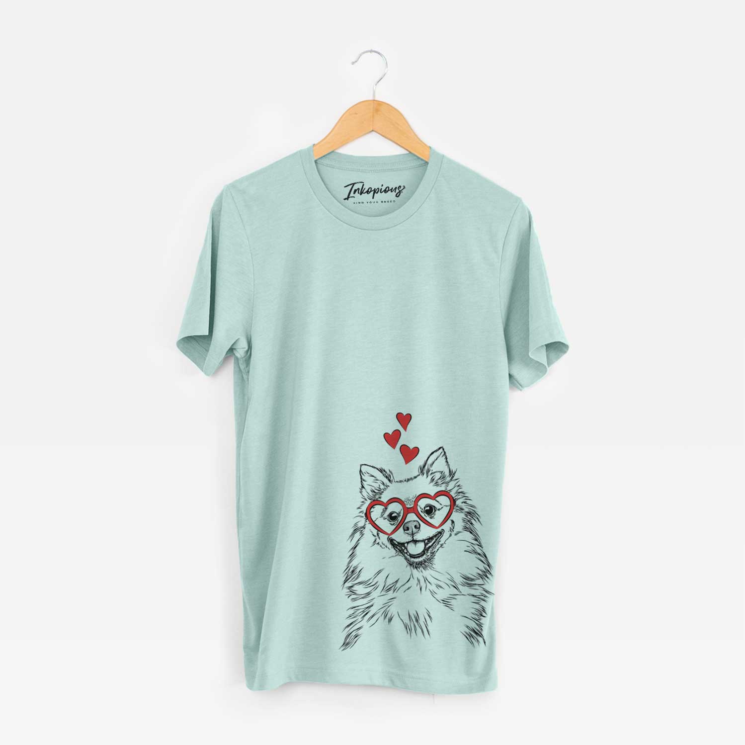 Hand-drawn sketch of Fibi the Spitz wearing heart-shaped glasses on a Heather Sage Unisex crewneck