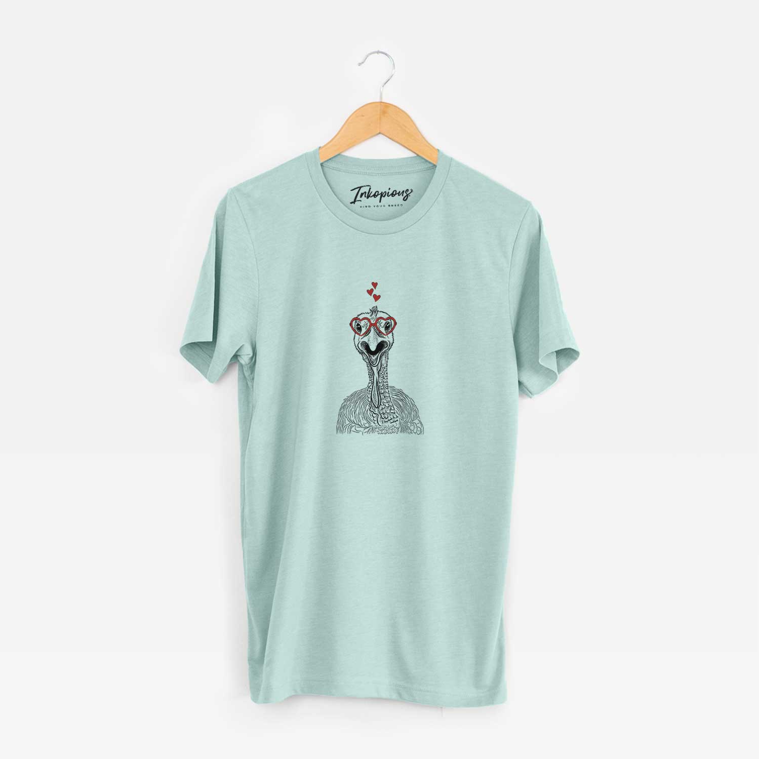 Hand-drawn sketch of Gobble the Turkey wearing heart-shaped glasses on a Heather Sage Unisex crewneck