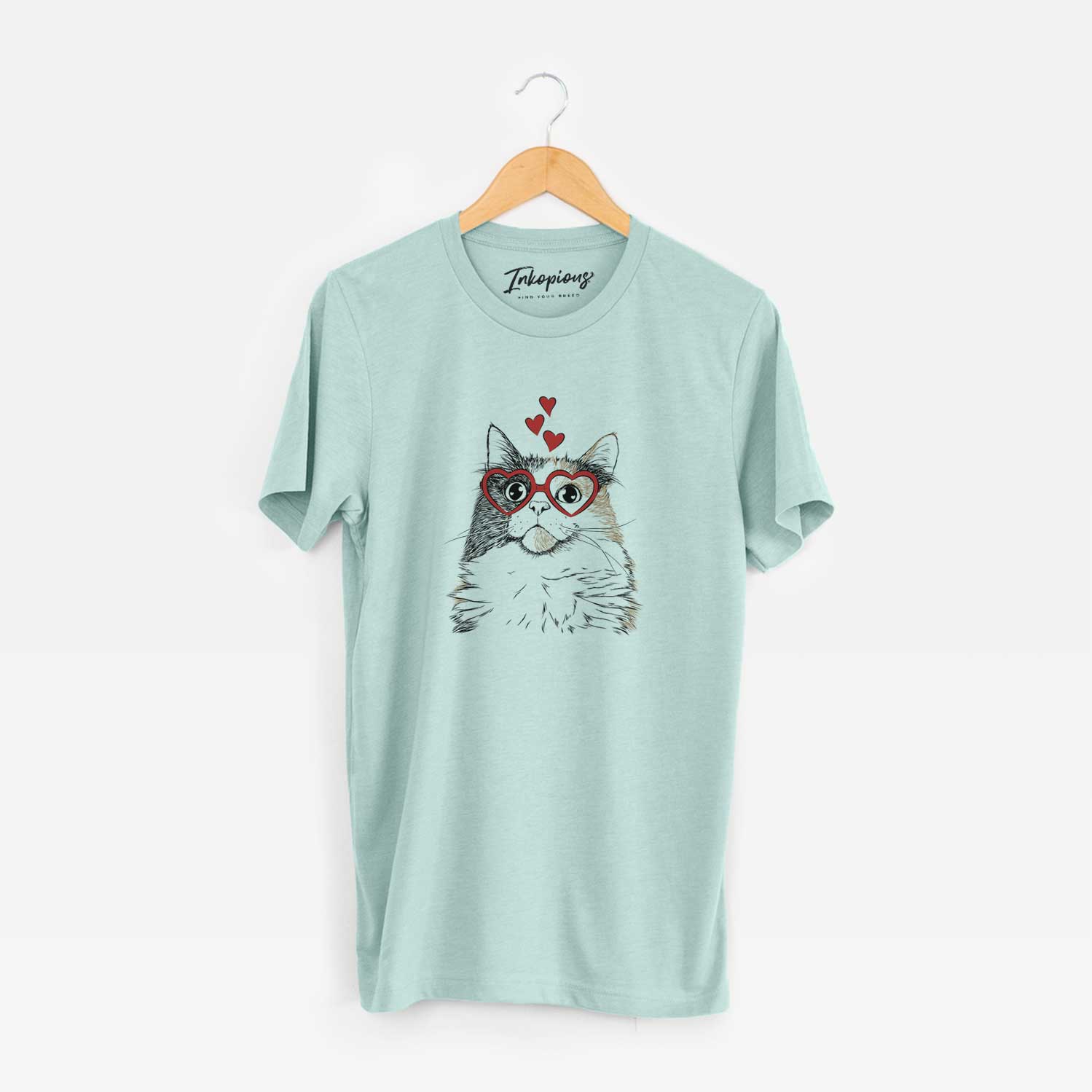 Hand-drawn sketch of Greta the Calico Cat wearing heart-shaped glasses on a Heather Sage Unisex crewneck