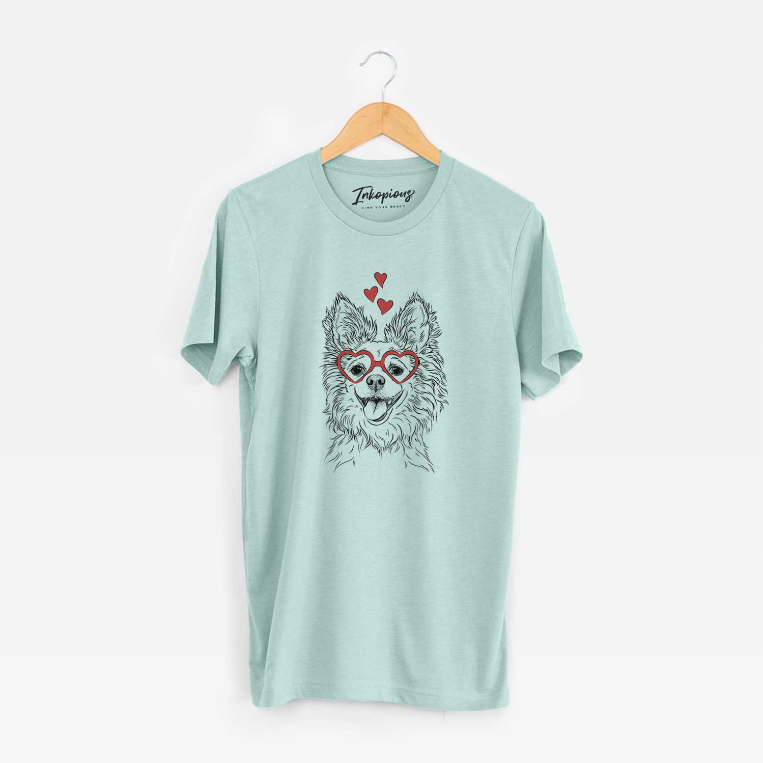 Hand-drawn sketch of Jasper the Pomchi wearing heart-shaped glasses on a Heather Sage Unisex crewneck