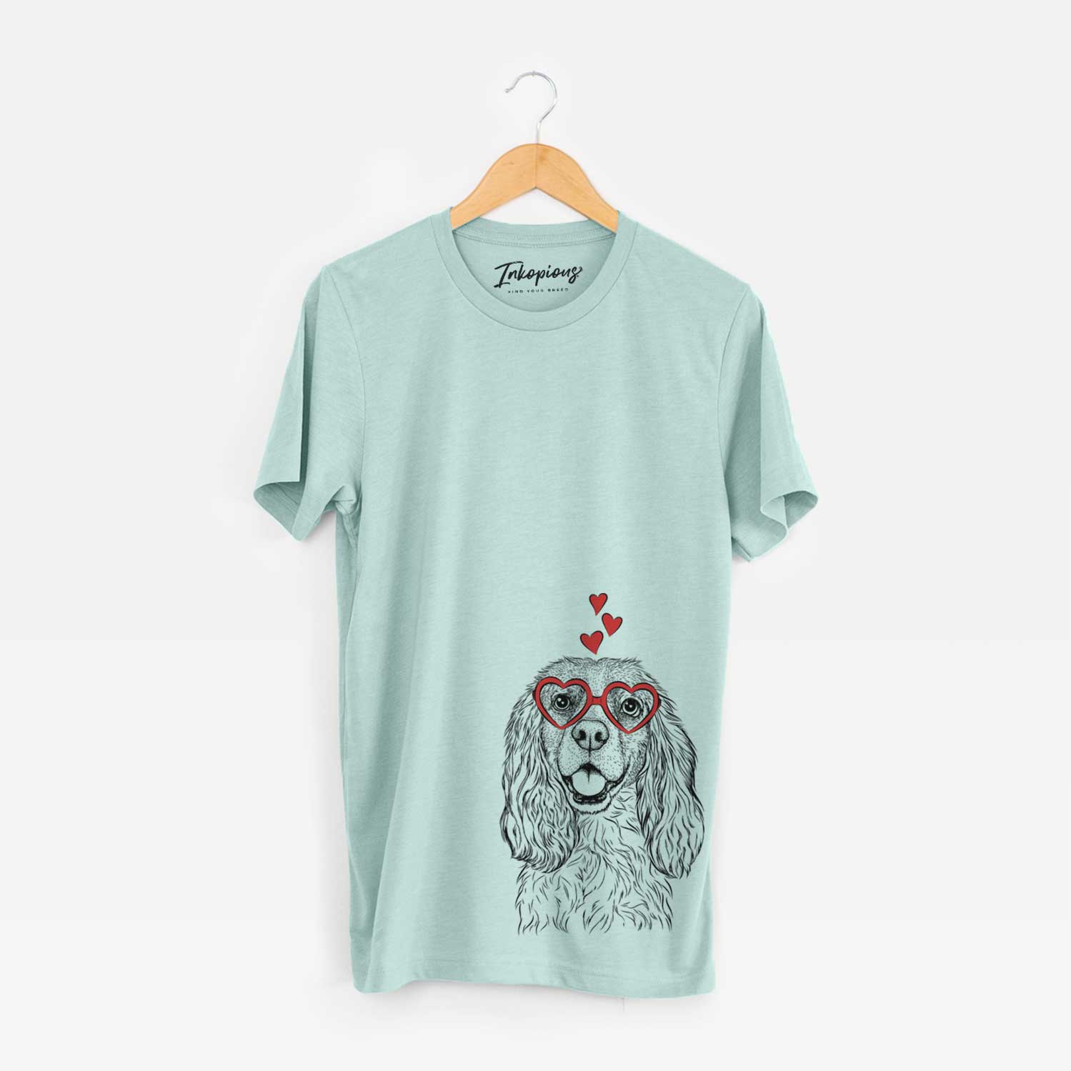 Hand-drawn sketch of Perry the Cockalier wearing heart-shaped glasses on a Heather Sage Unisex crewneck