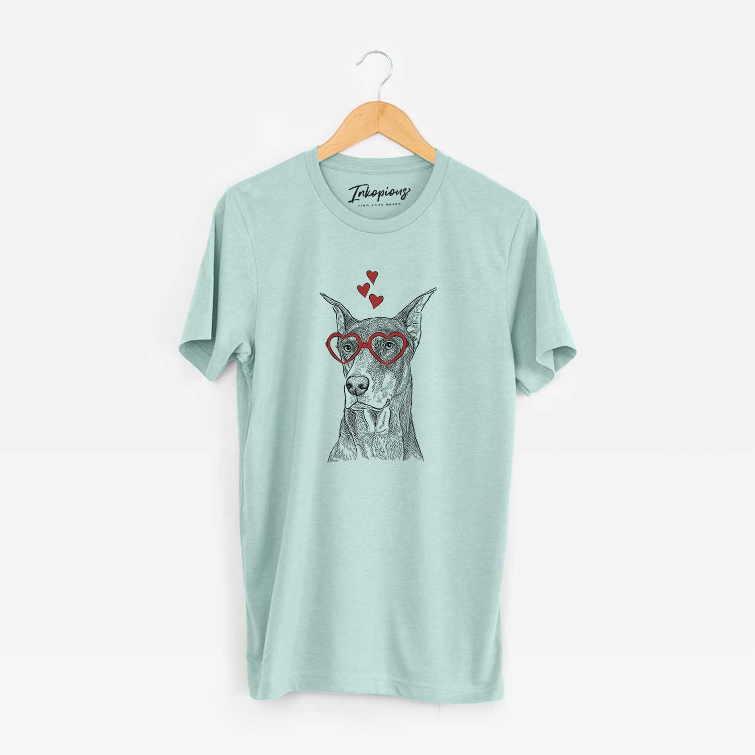 Hand-drawn sketch of RJ the Doberman Pinscher wearing heart-shaped glasses on a Heather Sage Unisex crewneck