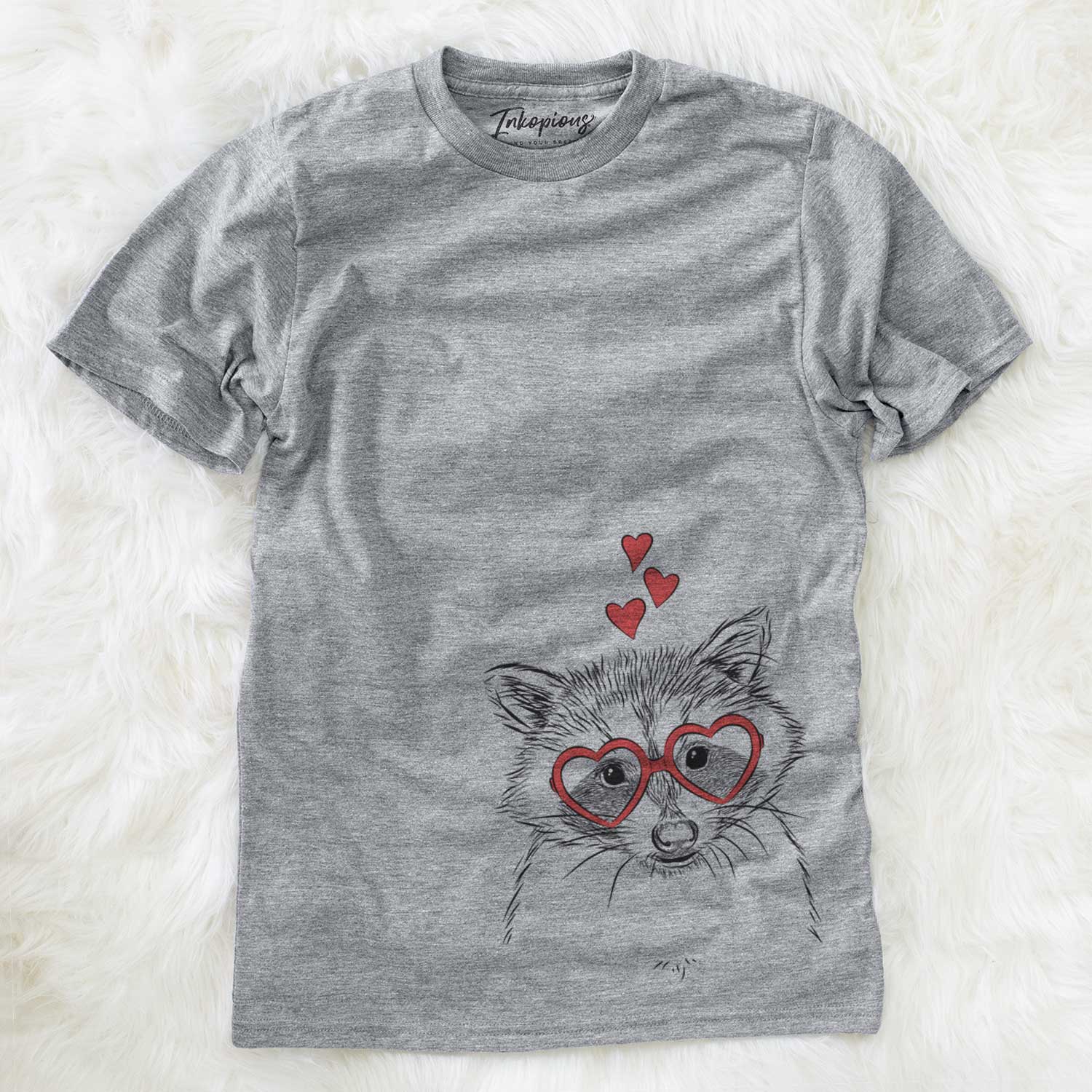 Hand-drawn sketch of Randy the Raccoon wearing heart-shaped glasses on a Grey Unisex crewneck