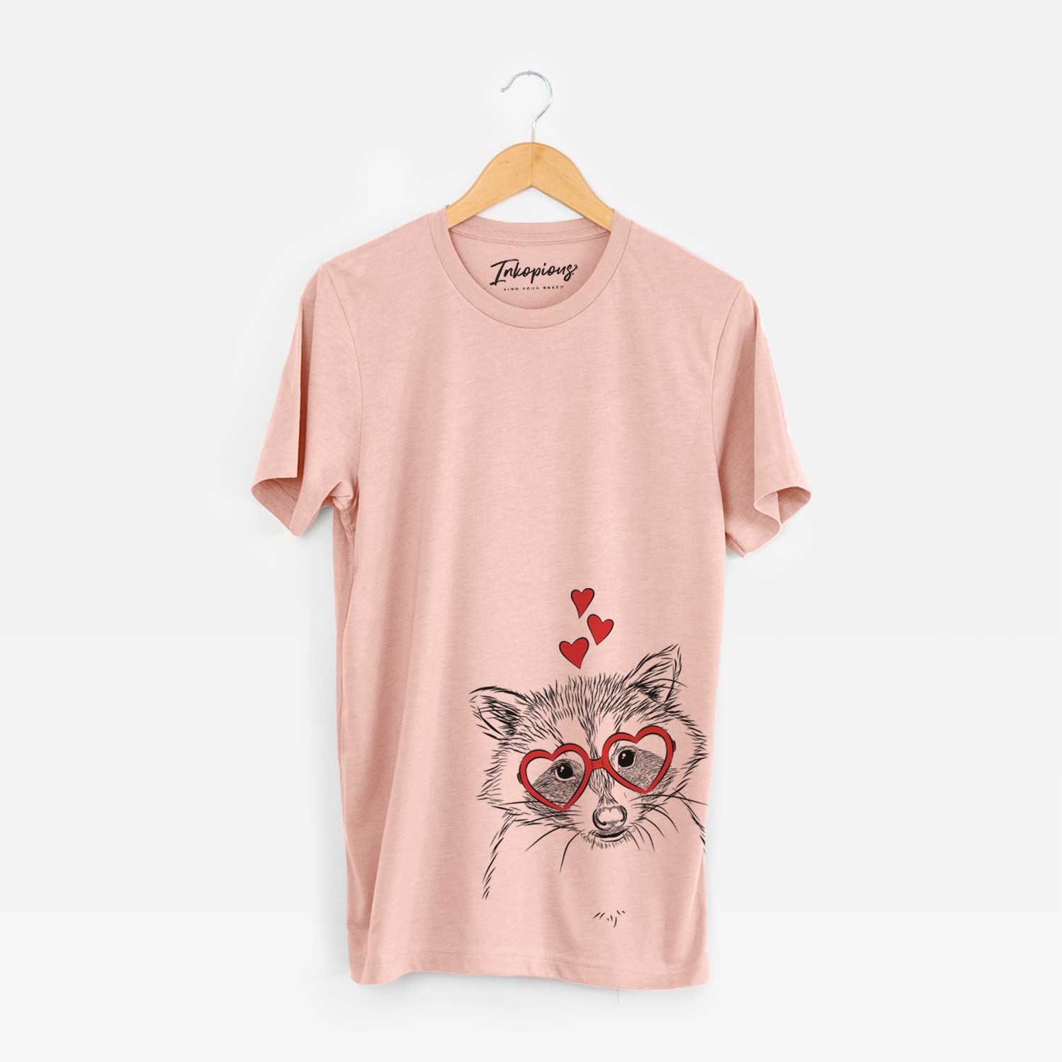 Hand-drawn sketch of Randy the Raccoon wearing heart-shaped glasses on a Peach Unisex crewneck