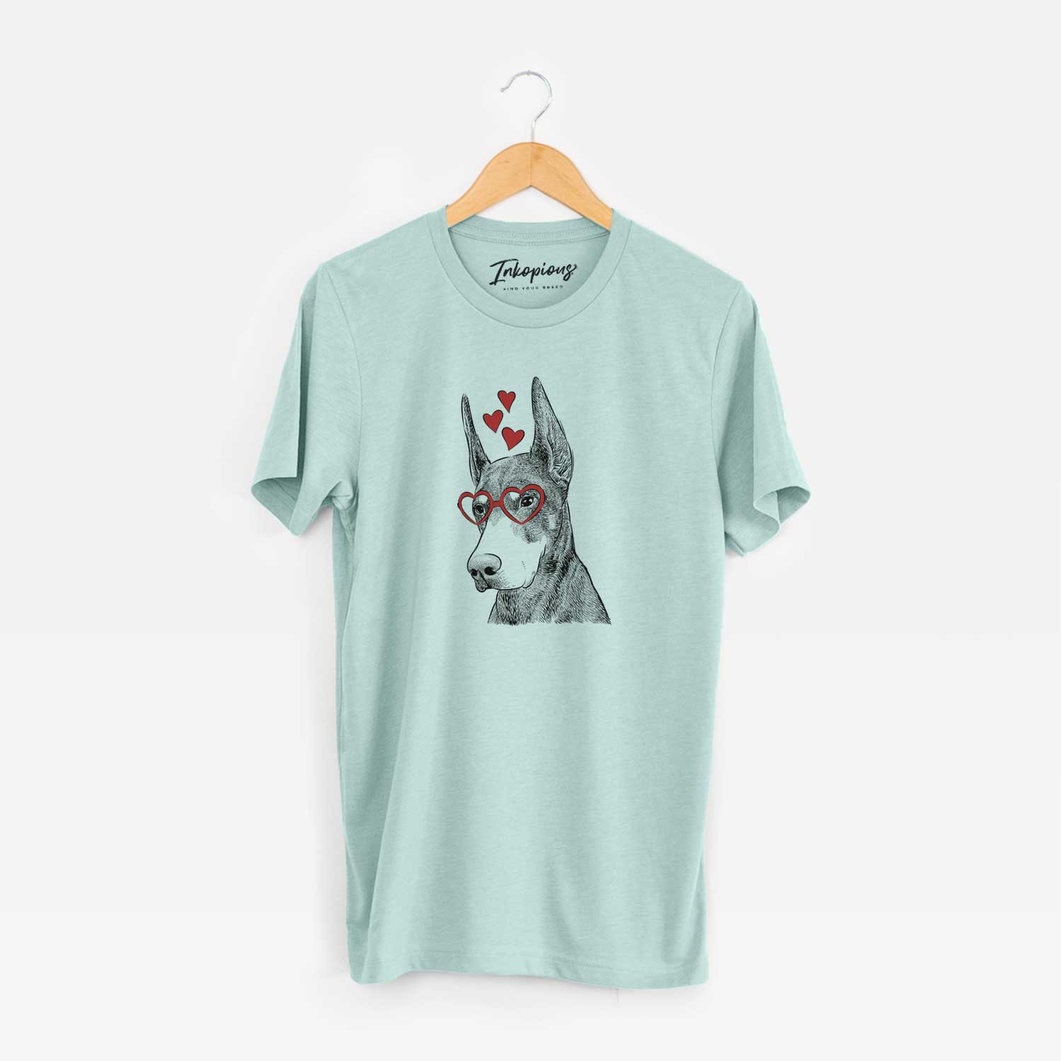 Hand-drawn sketch of Sunny the Doberman Pinscher wearing heart-shaped glasses on a Heather Sage Unisex crewneck