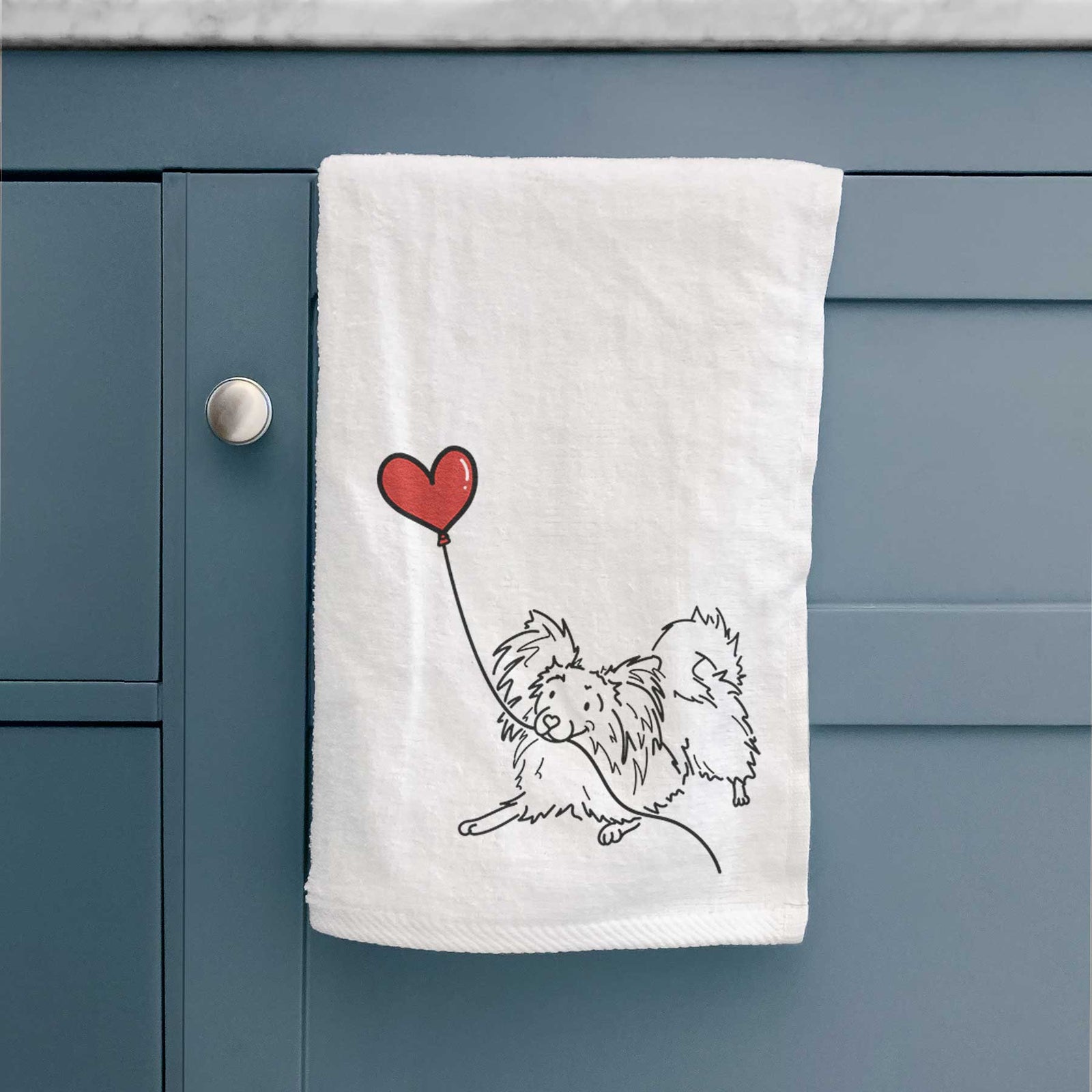 Minimalist line drawing of a Papillon Heart String holding a heart balloon on a decorative hand towel