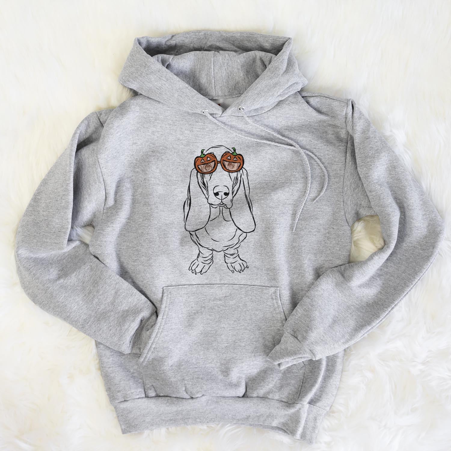 Hand-drawn sketch of Charlie the Basset Hound wearing pumpkin glasses on a Grey pumpkin collection, flat lay