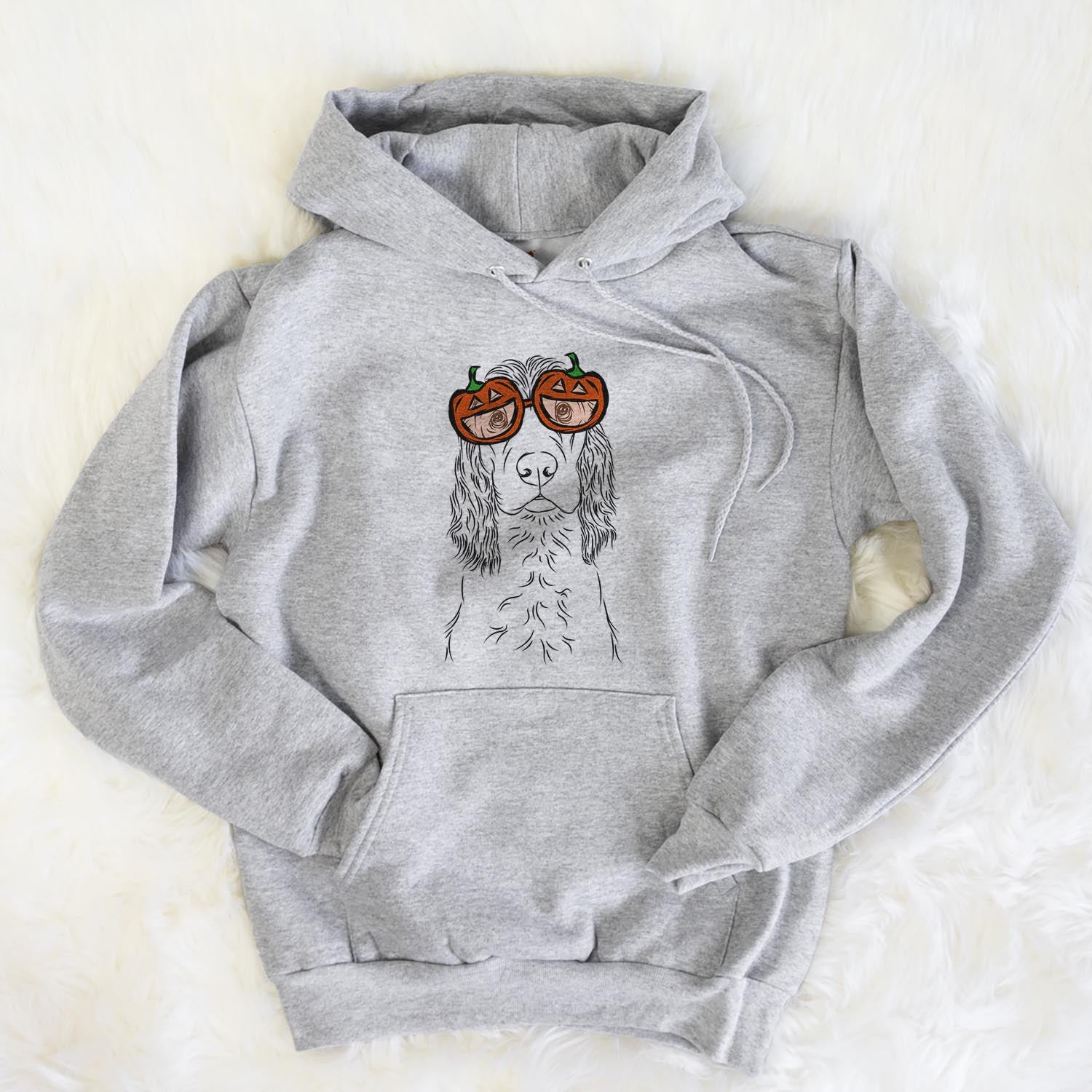 Hand-drawn sketch of Logan the Cocker Spaniel wearing pumpkin glasses on a Grey pumpkin collection, flat lay