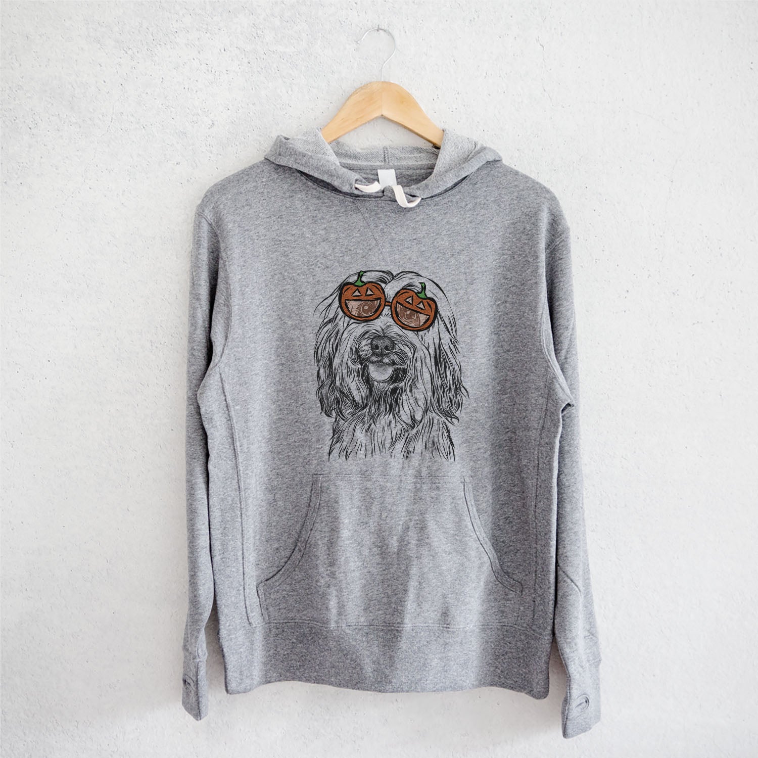 Hand-drawn sketch of Rime the Tibetan Terrier wearing pumpkin glasses on a Grey pumpkin collection, on a hanger