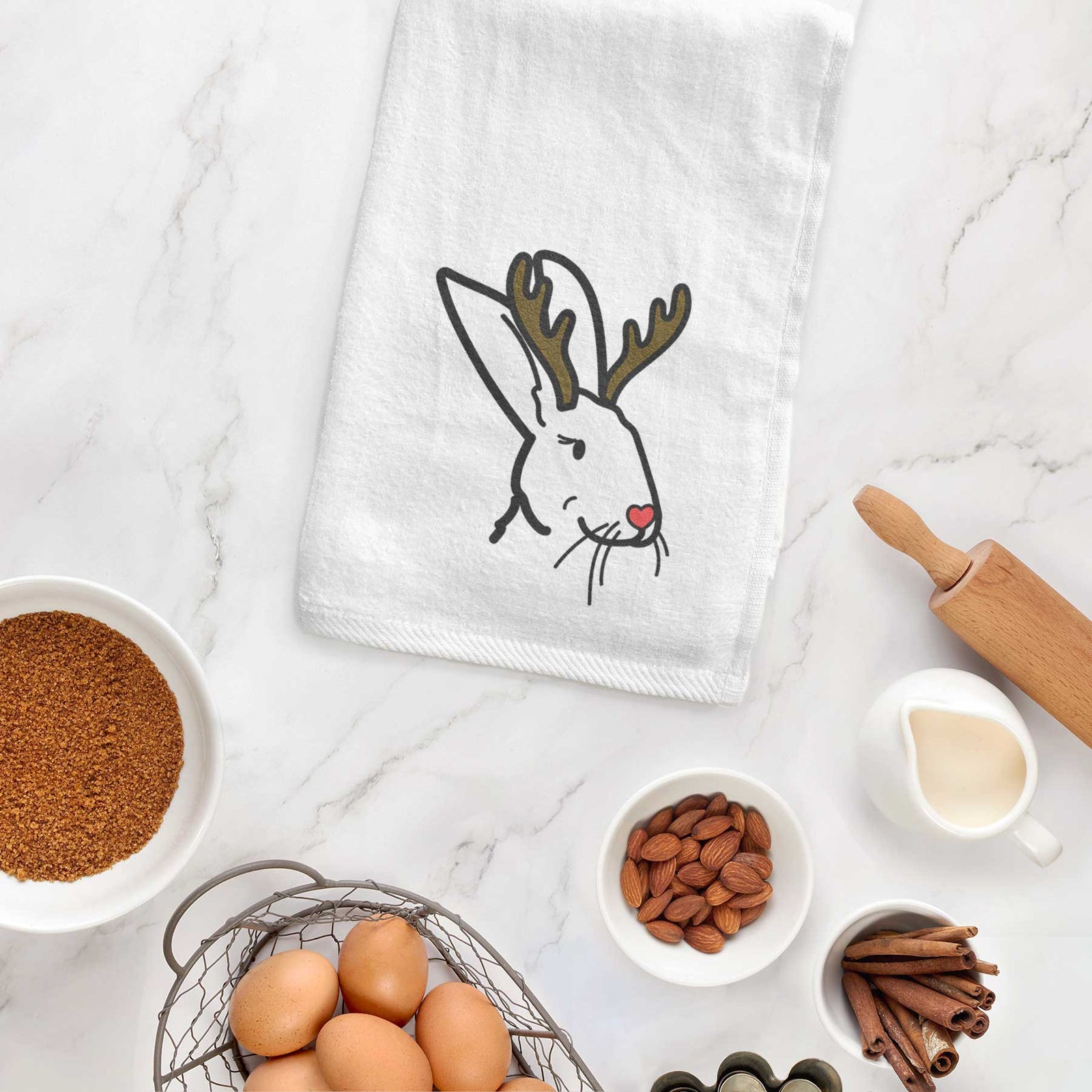 Minimalist line drawing of Betsy the Rex Rabbit with reindeer antlers and a red nose on a decorative hand towel