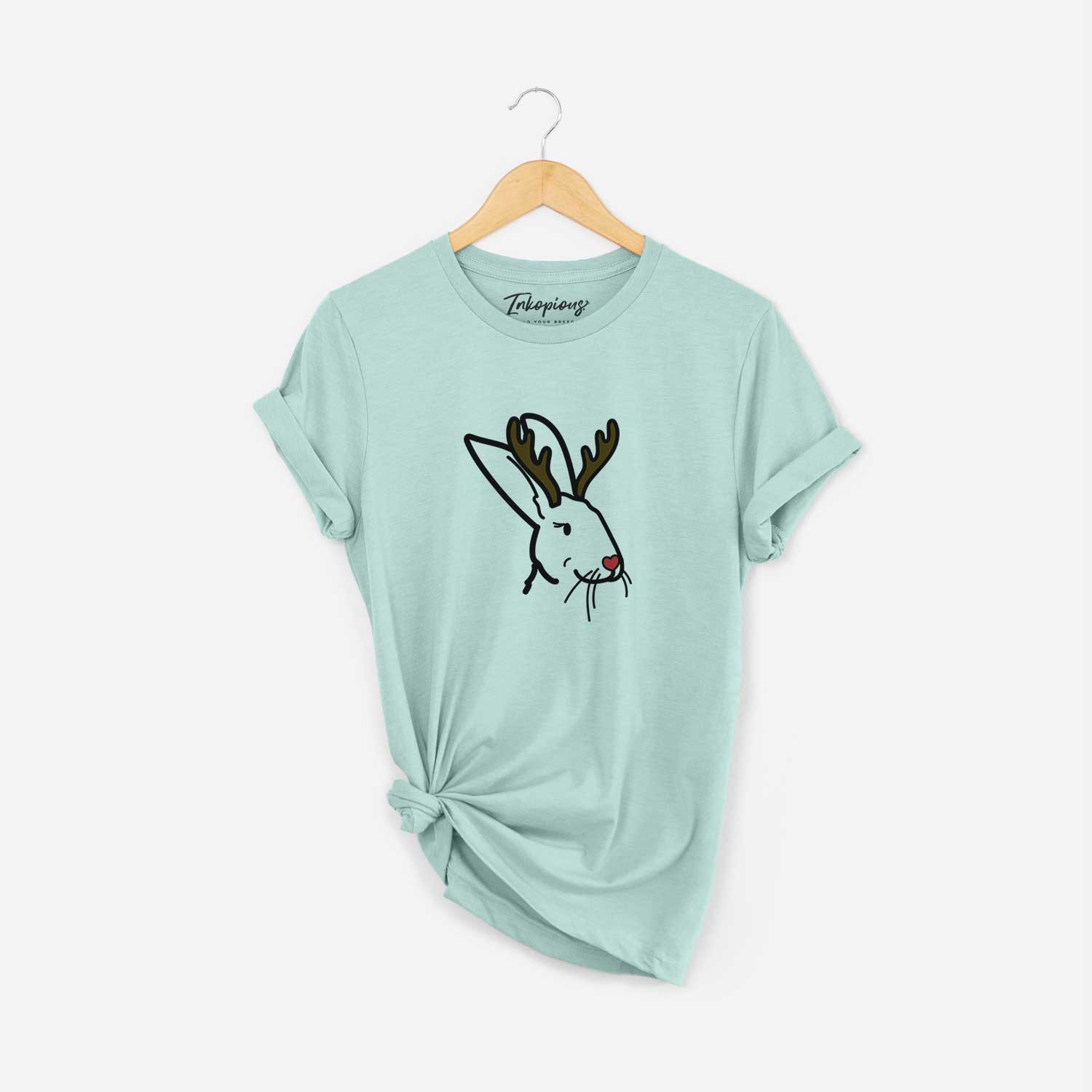 Minimalist line drawing of Betsy the Rex Rabbit with reindeer antlers and a red nose on a Heather Sage Unisex crewneck