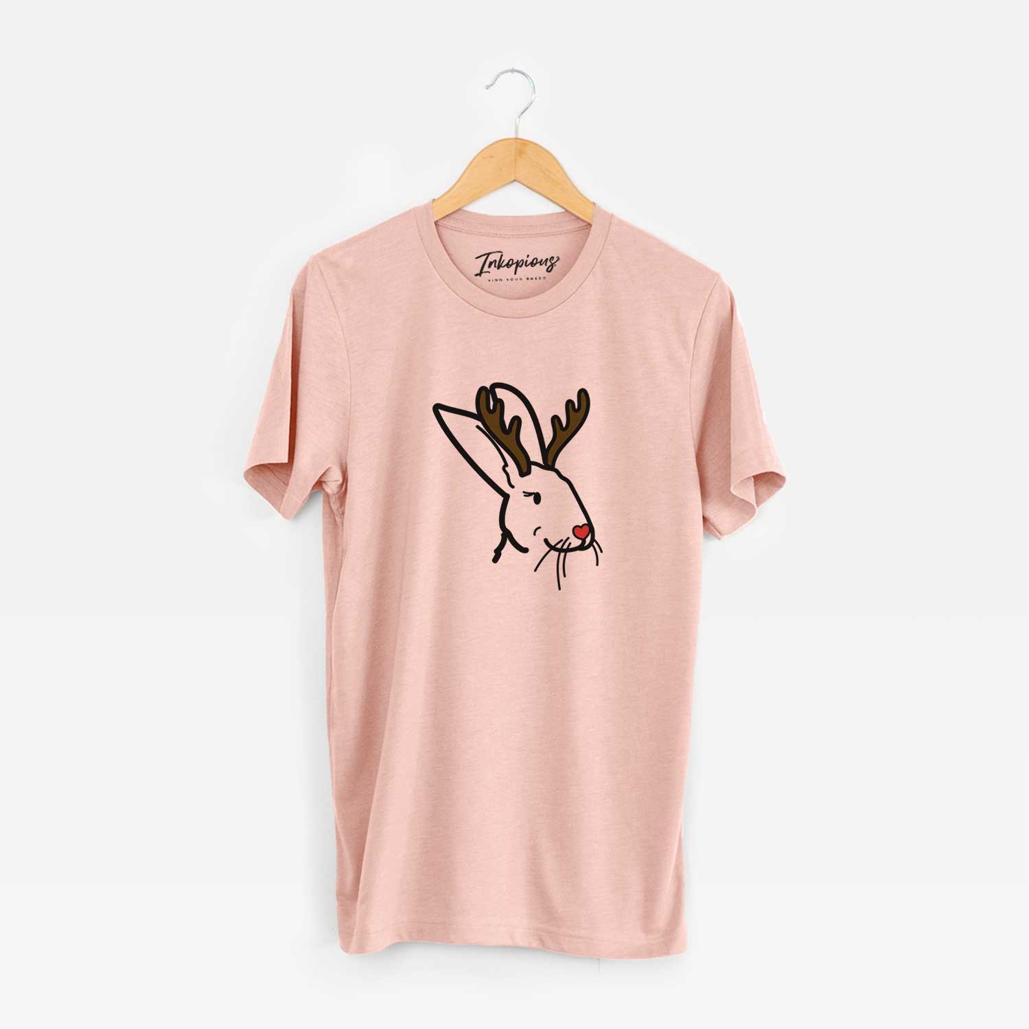 Minimalist line drawing of Betsy the Rex Rabbit with reindeer antlers and a red nose on a Peach Unisex crewneck