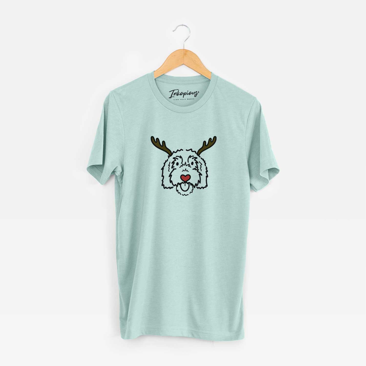 Minimalist line drawing of Gus the Goldendoodle with reindeer antlers and a red nose on a Heather Sage Unisex crewneck