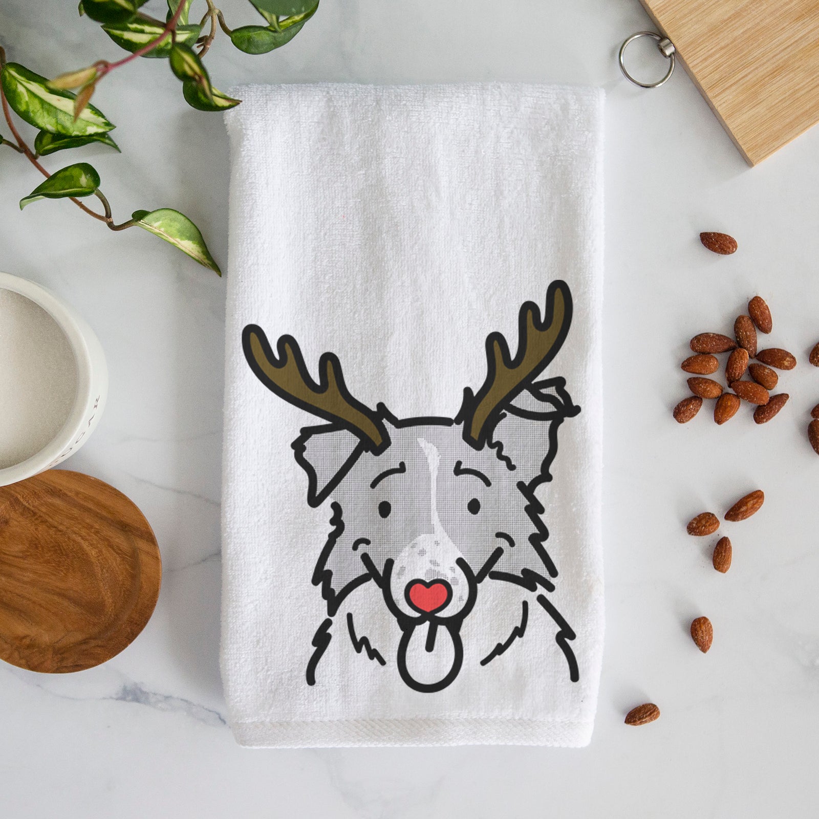 Minimalist line drawing of Jam the Border Collie with reindeer antlers and a red nose on a decorative hand towel