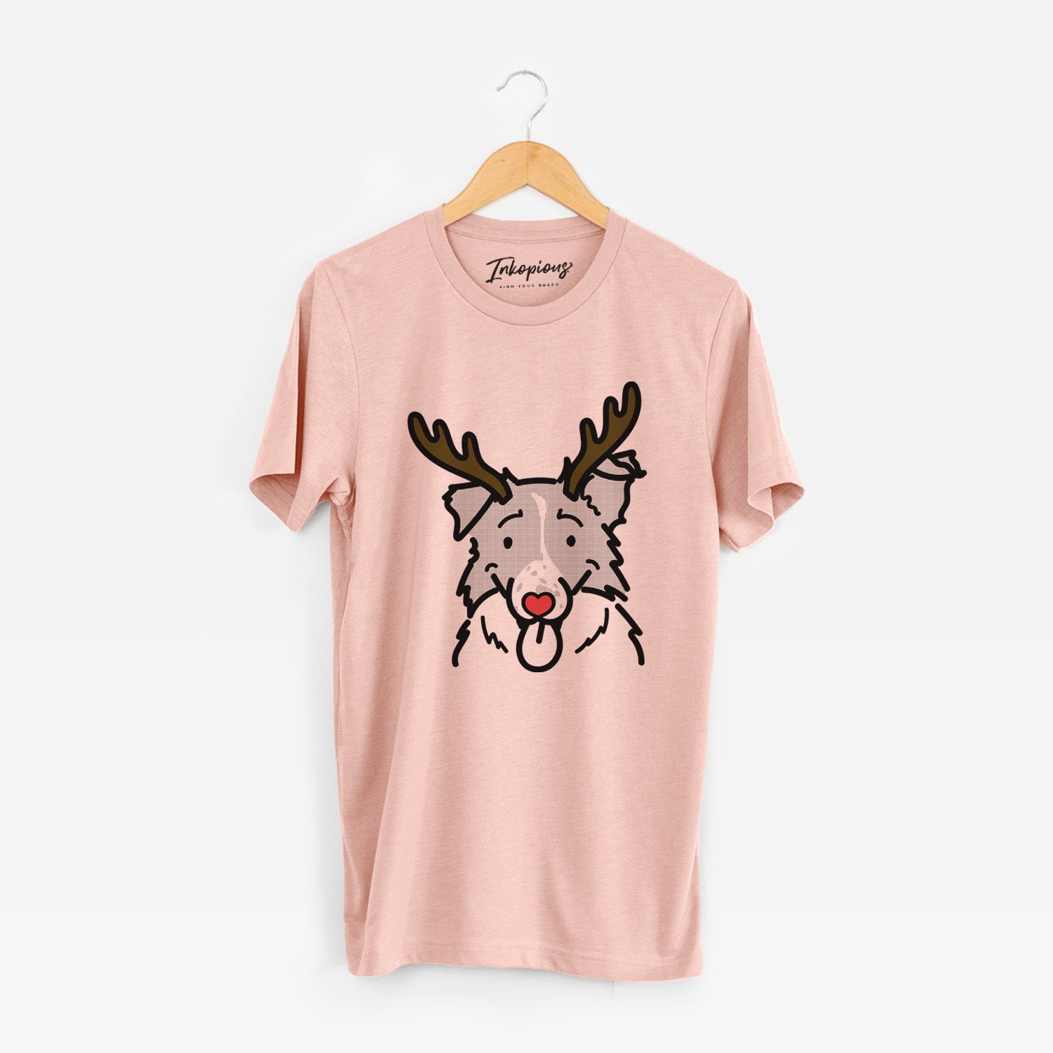 Minimalist line drawing of Jam the Border Collie with reindeer antlers and a red nose on a Peach Unisex crewneck