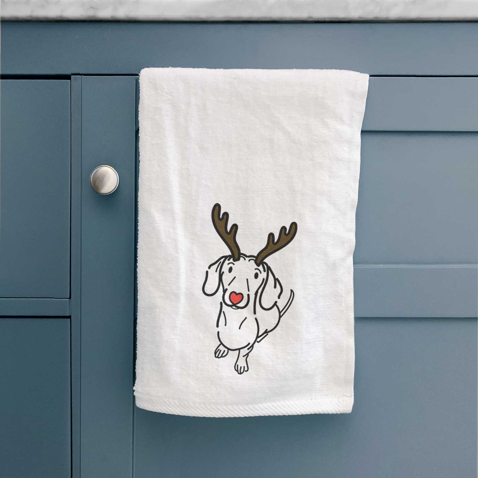 Minimalist line drawing of Moxie the Dachshund with reindeer antlers and a red nose on a decorative hand towel