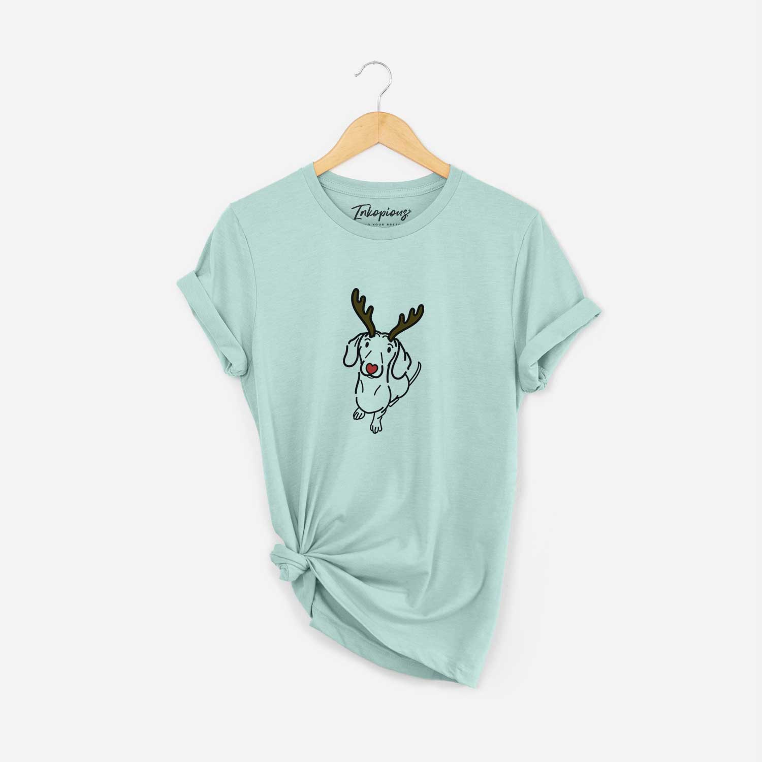 Minimalist line drawing of Moxie the Dachshund with reindeer antlers and a red nose on a Heather Sage Unisex crewneck